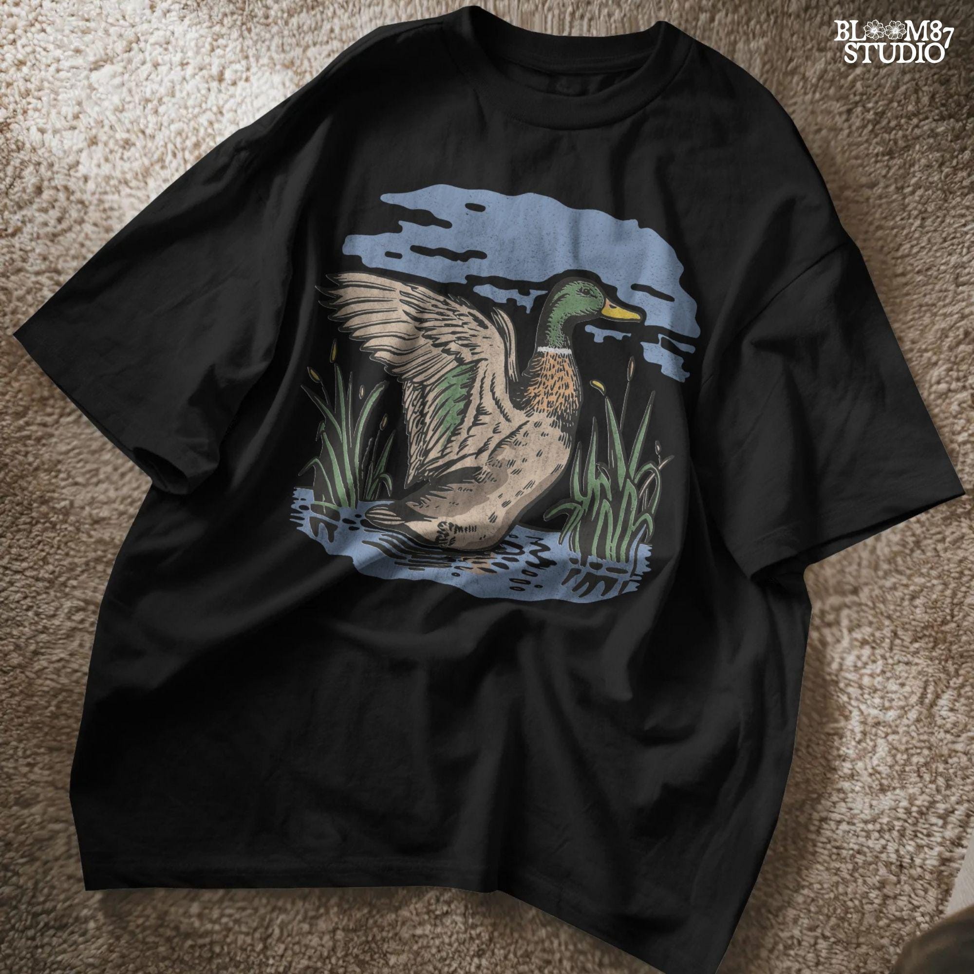 Vintage illustration of a mallard duck with wings spread standing in a pond with reeds and a cloudy blue sky – rustic nature sublimation PNG.