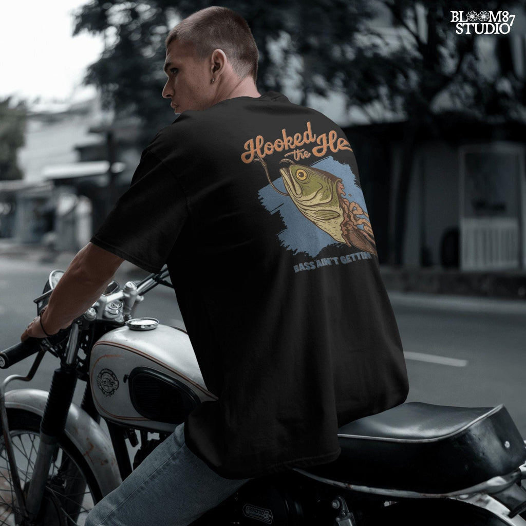 Funny exaggerated bass fish graphic with a hook through its mouth and dramatic detailing, paired with the text “Hooked the Hell” and “Bass Ain’t Gettin Back.”