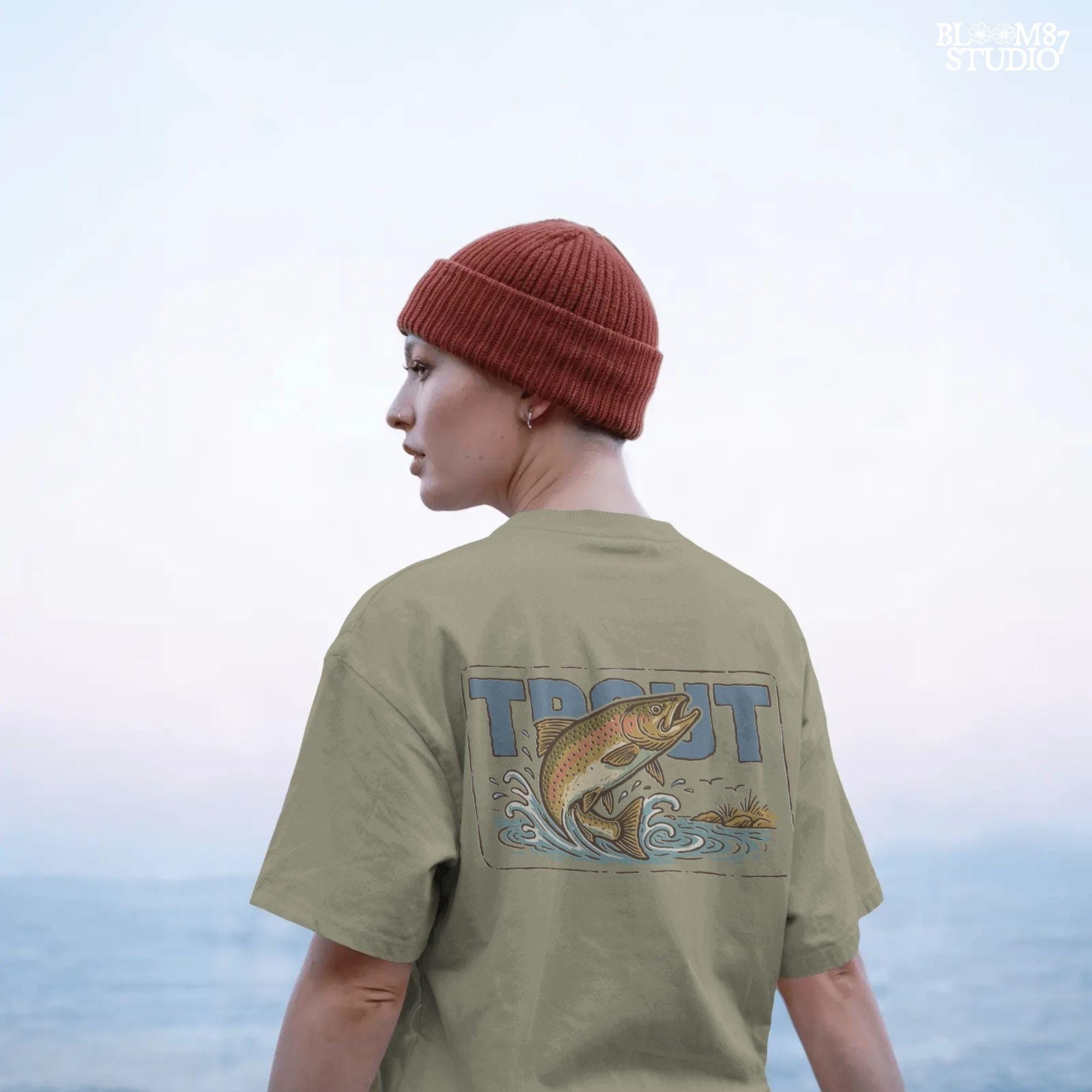 Vintage-style illustration of a rainbow trout jumping from the water in front of bold block letters spelling “TROUT”.