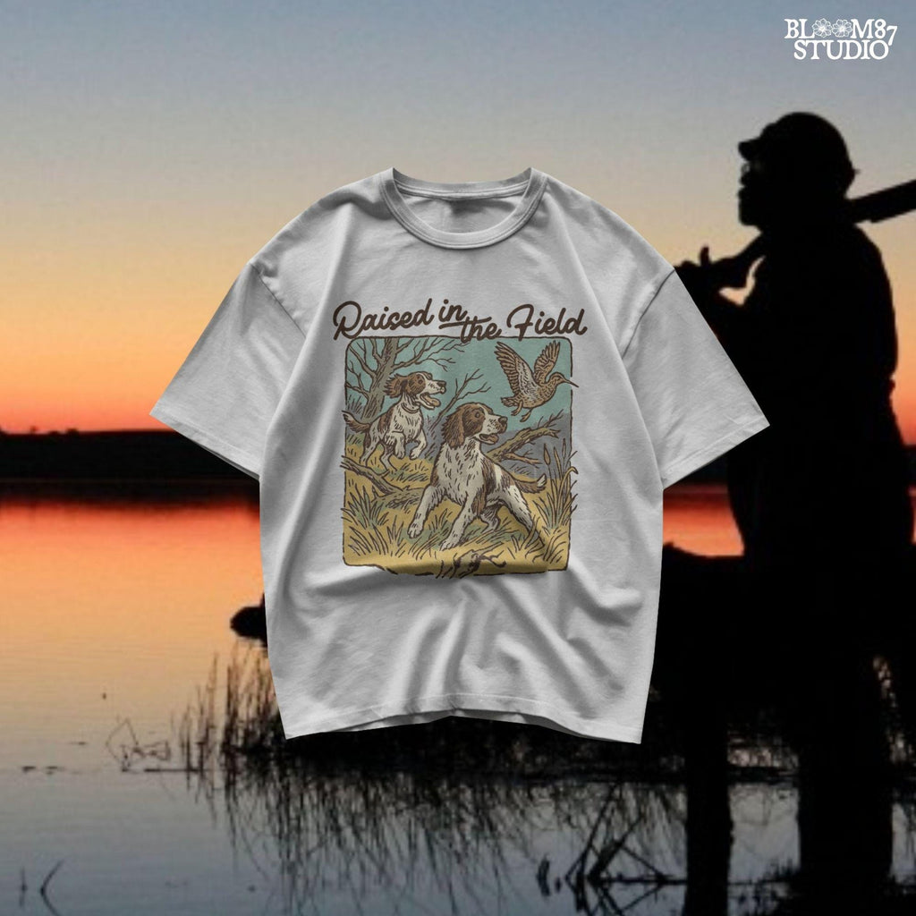 Rustic illustration of two Springer Spaniels flushing a game bird with the phrase “Raised in the Field” in vintage script.