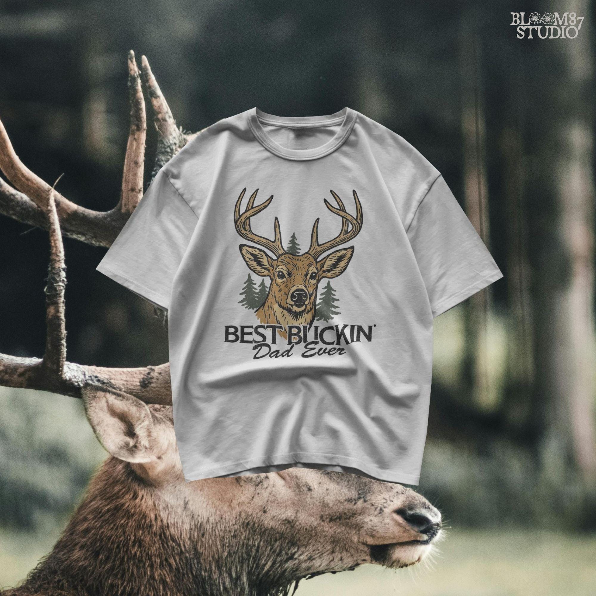 Rustic illustration of a buck deer with antlers and pine trees, text below says “Best Buckin’ Dad Ever” in bold and script font