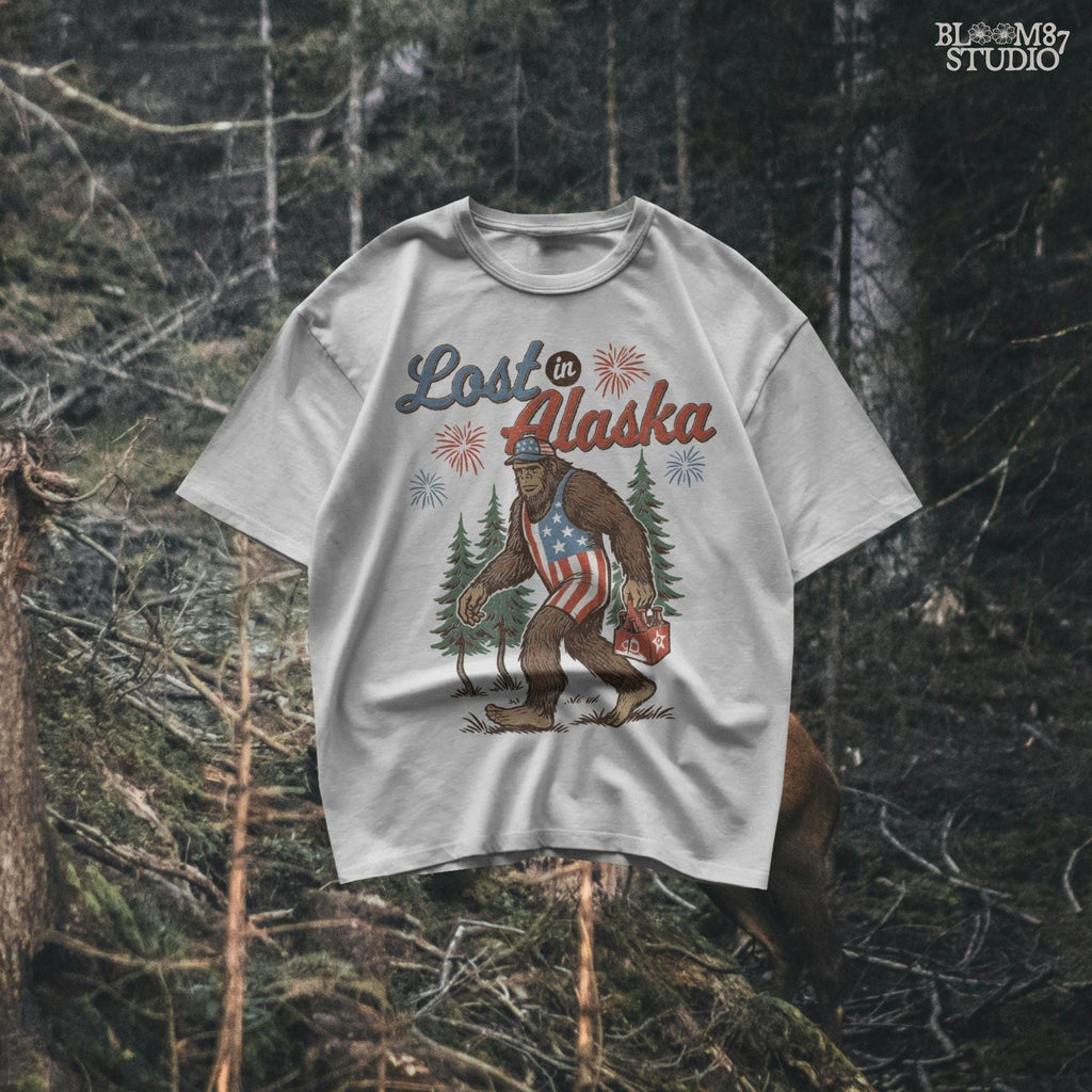 Bigfoot wearing an American flag outfit and cap, walking through forest with fireworks in background, holding a six-pack of beer with “Lost in Alaska” text