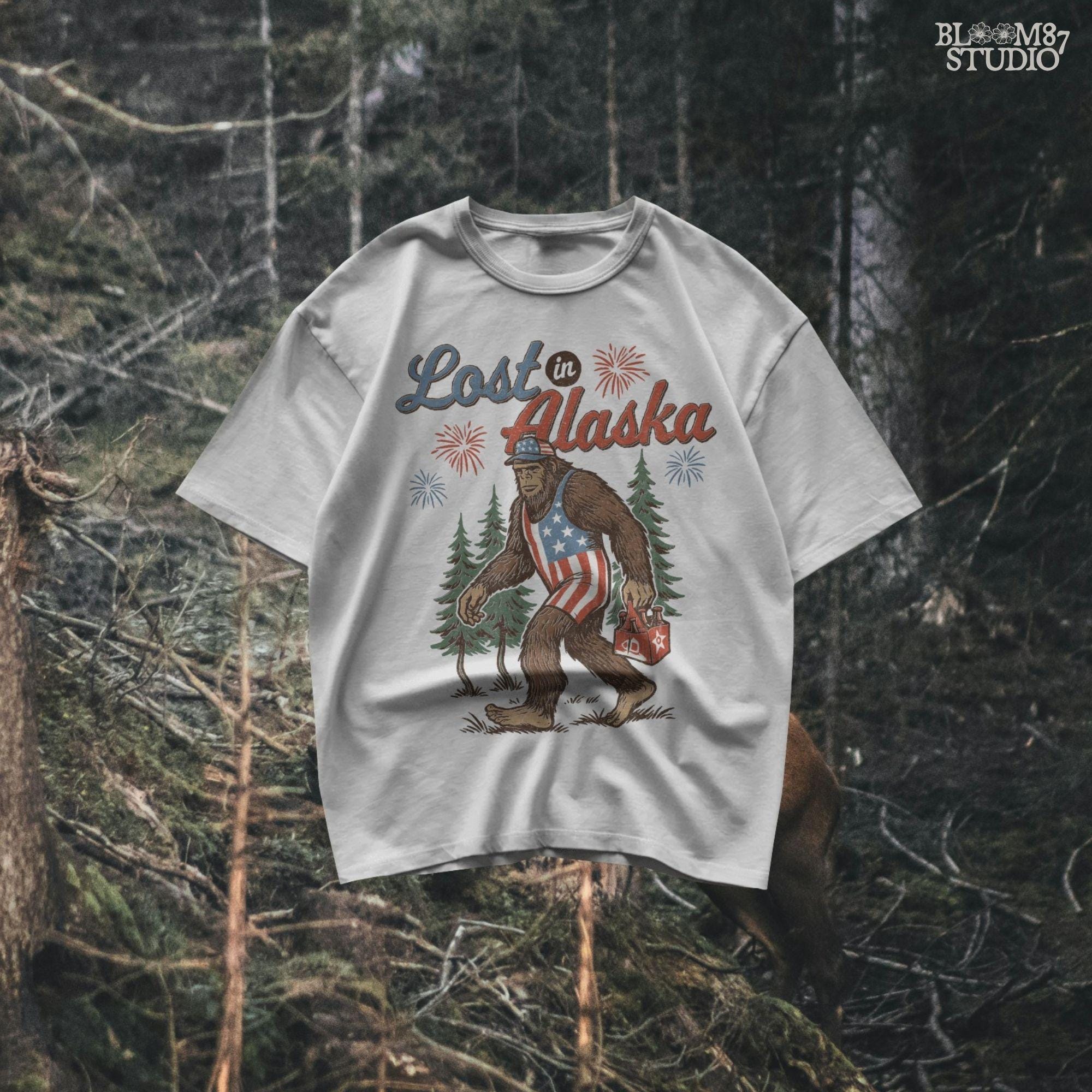 Bigfoot wearing an American flag outfit and cap, walking through forest with fireworks in background, holding a six-pack of beer with “Lost in Alaska” text