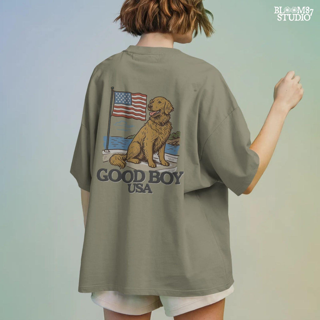 Golden retriever sitting proudly in front of the American flag with “Good Boy USA” text below, patriotic dog design