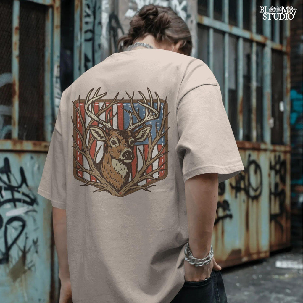 Illustration of a proud buck with large antlers standing in front of a stitched American flag patch, rustic hunting style.