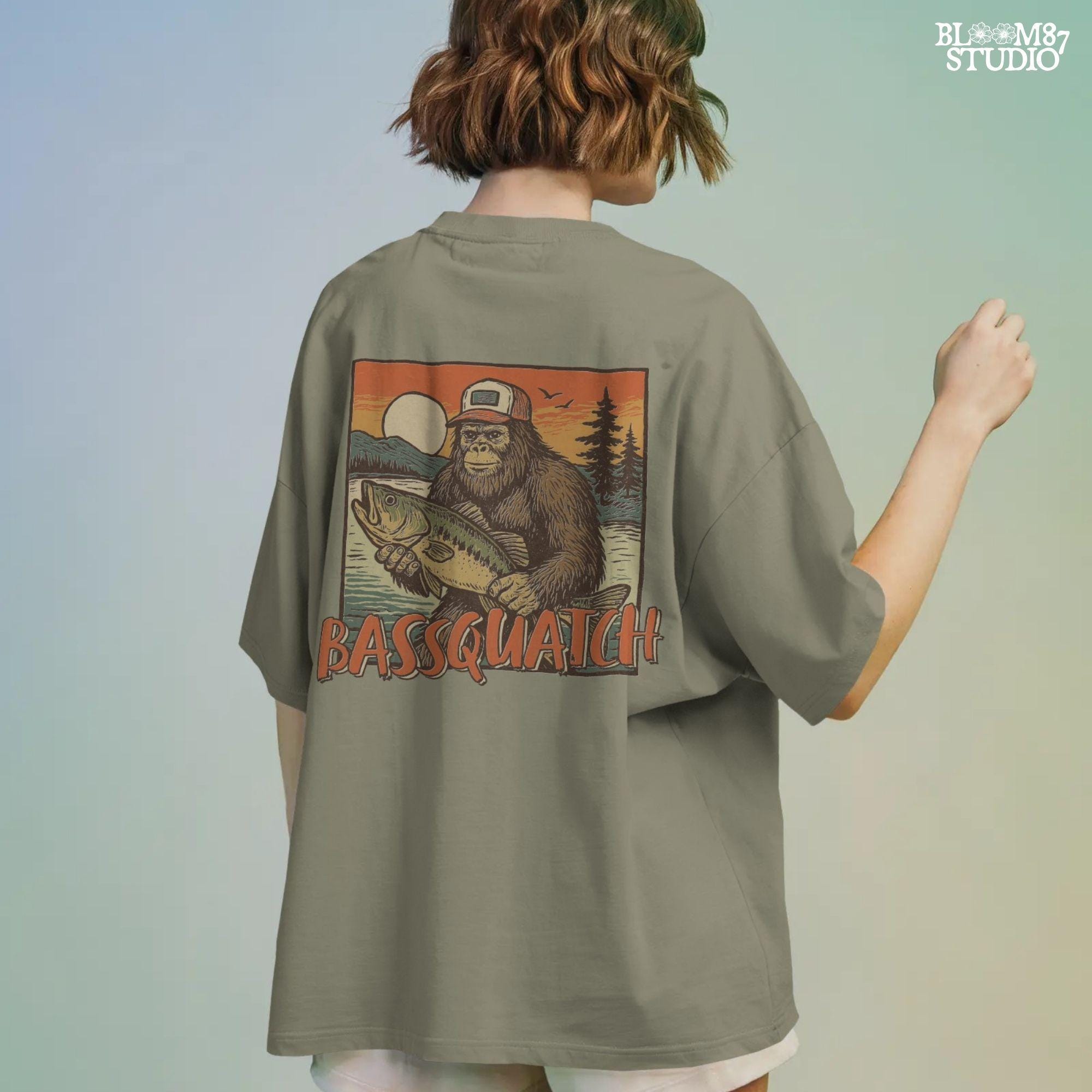 Bigfoot holding a large bass at sunset with summer lake background and the word “Bassquatch” in bold orange letters.