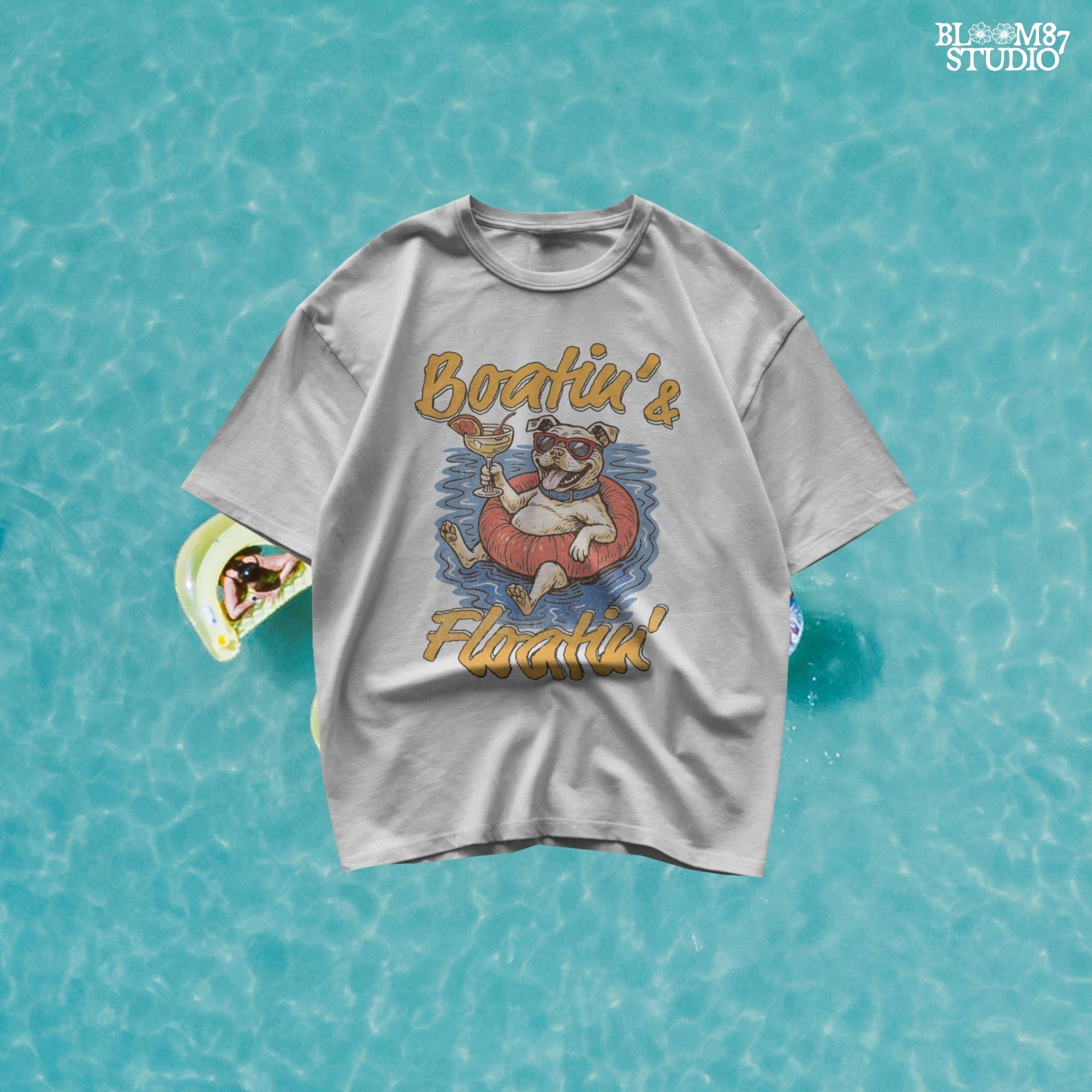 Cartoon bulldog in red sunglasses floating on a tube, holding a margarita, with “Boatin’ & Floatin’” summer text.