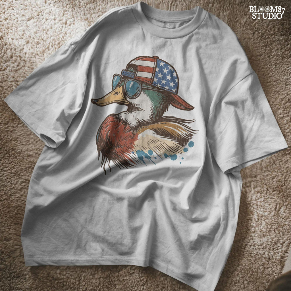 Cartoon mallard duck wearing American flag hat and sunglasses in a humorous patriotic style, with bold colors and splash detail