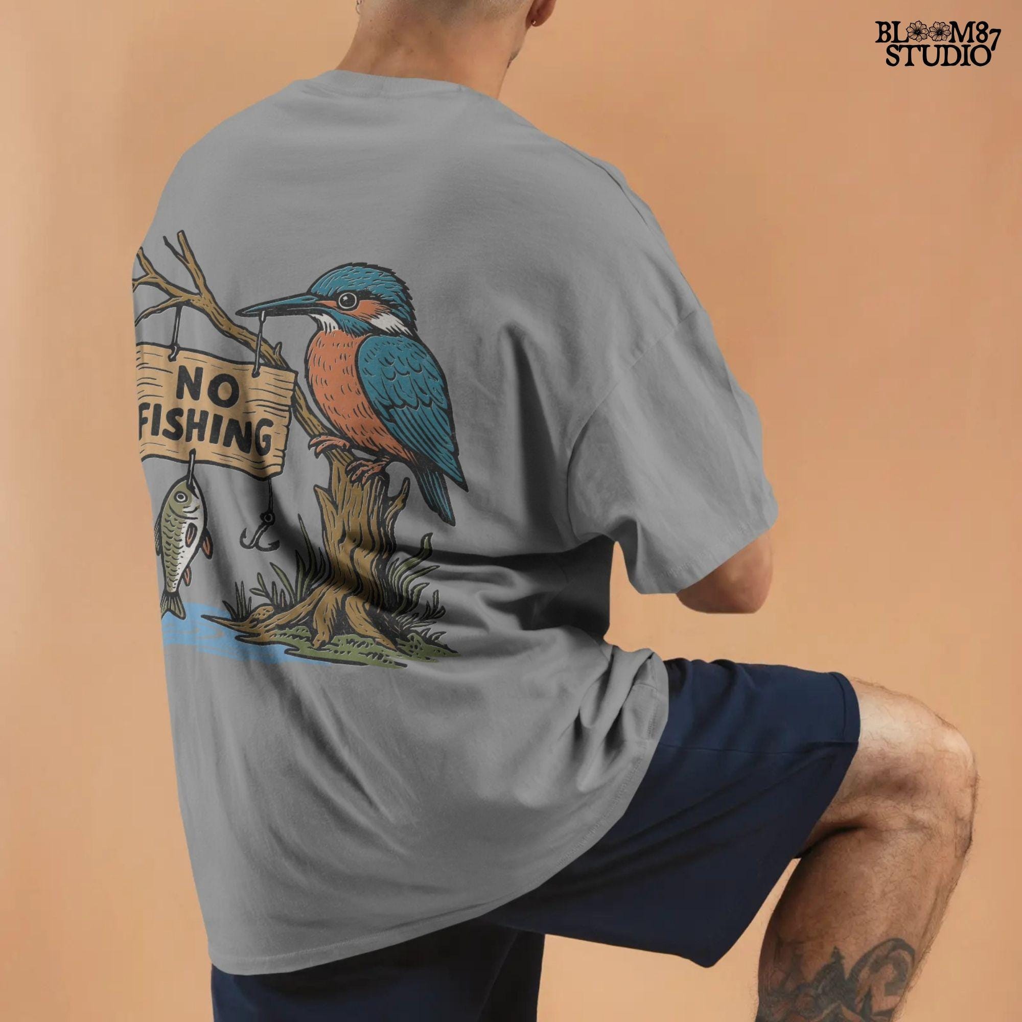 Cartoon kingfisher bird sitting on a tree holding a “No Fishing” sign with a fish hanging below, in a humorous lake life design