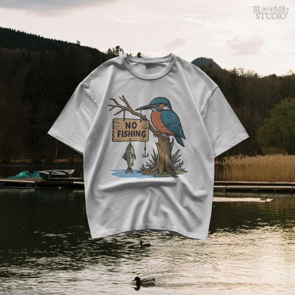 Cartoon kingfisher bird sitting on a tree holding a “No Fishing” sign with a fish hanging below, in a humorous lake life design