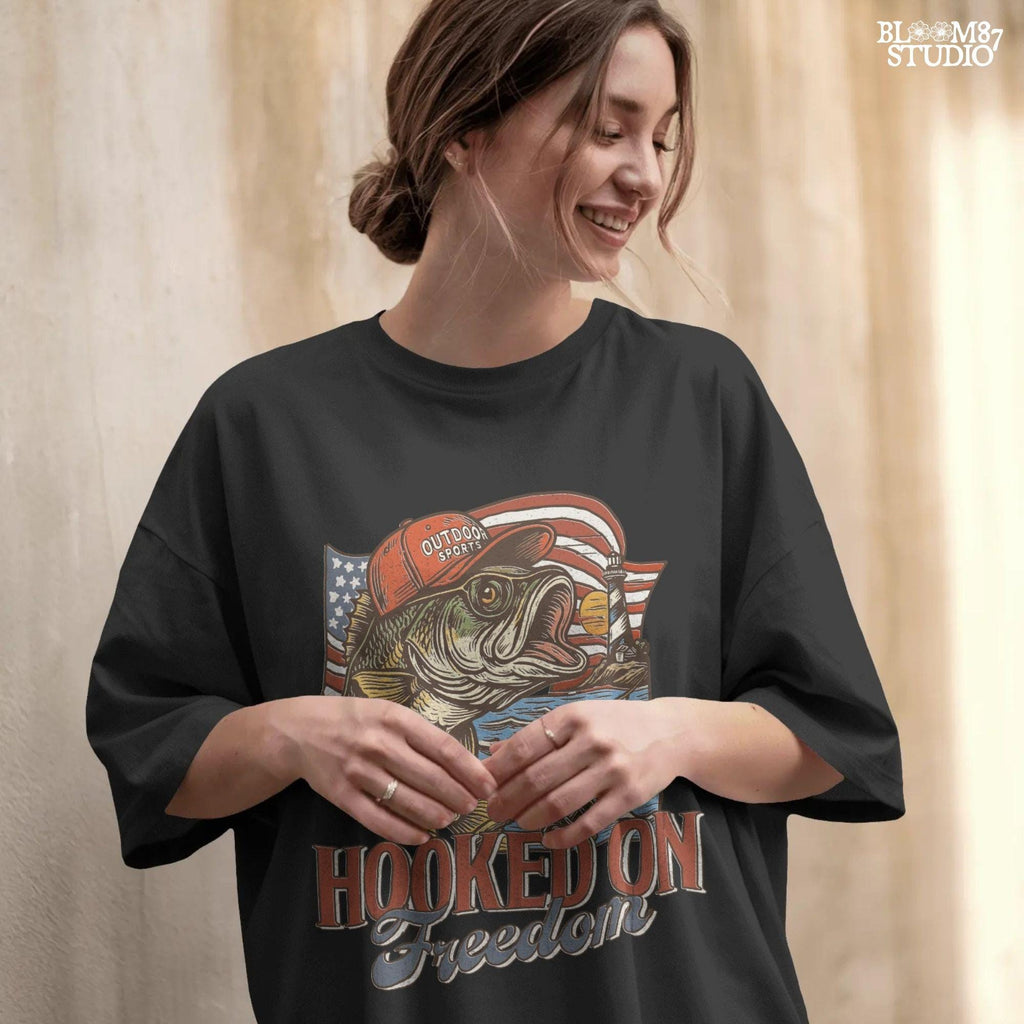 Patriotic bass fish wearing red cap with American flag, lighthouse, and “Hooked on Freedom” text – ideal for 4th of July fishing designs.