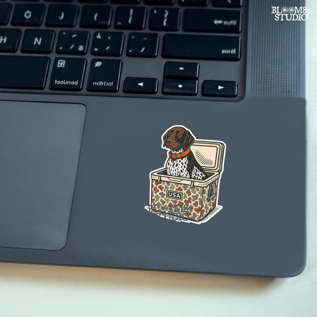 German Shorthaired Pointer dog sitting inside camouflage cooler labeled “USA,” in rustic cartoon patriotic style