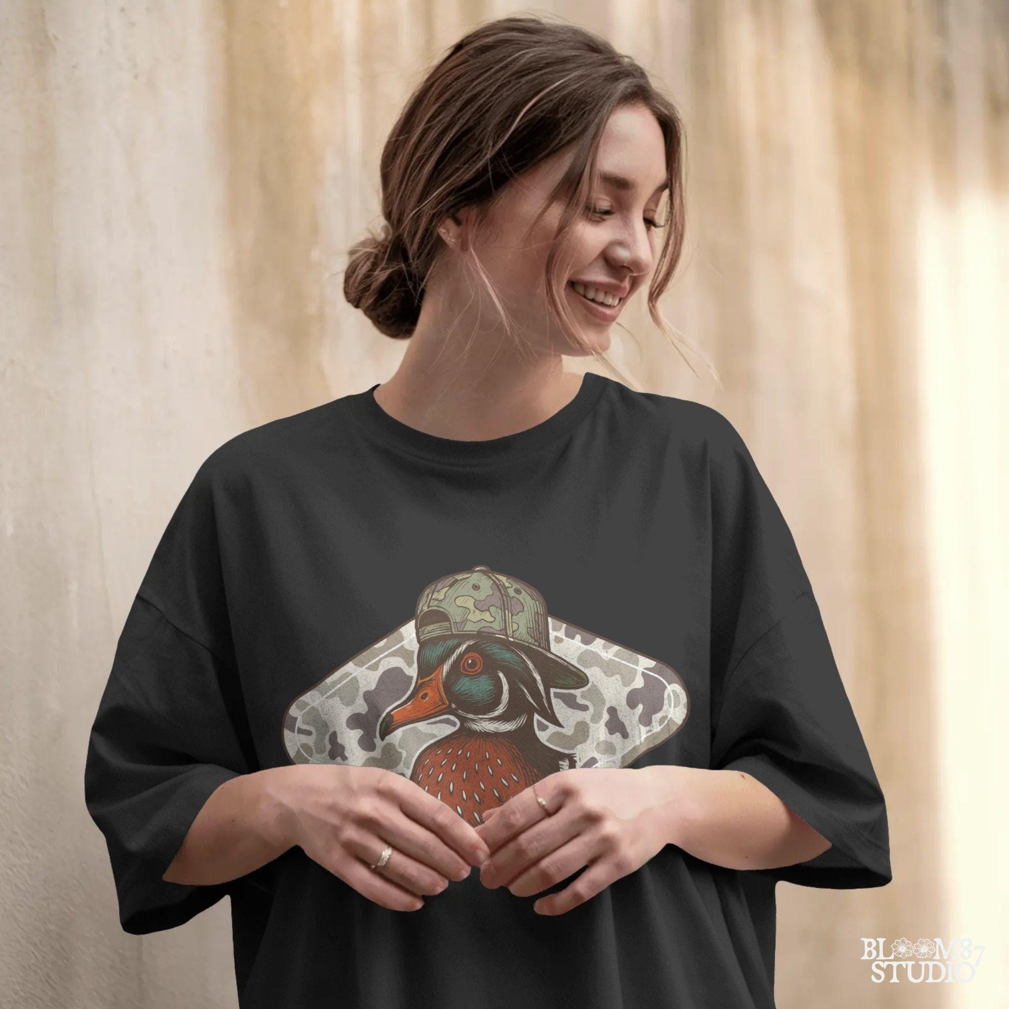 Funny wood duck wearing camo hat in front of marsh camo background – southern hunting sublimation design.