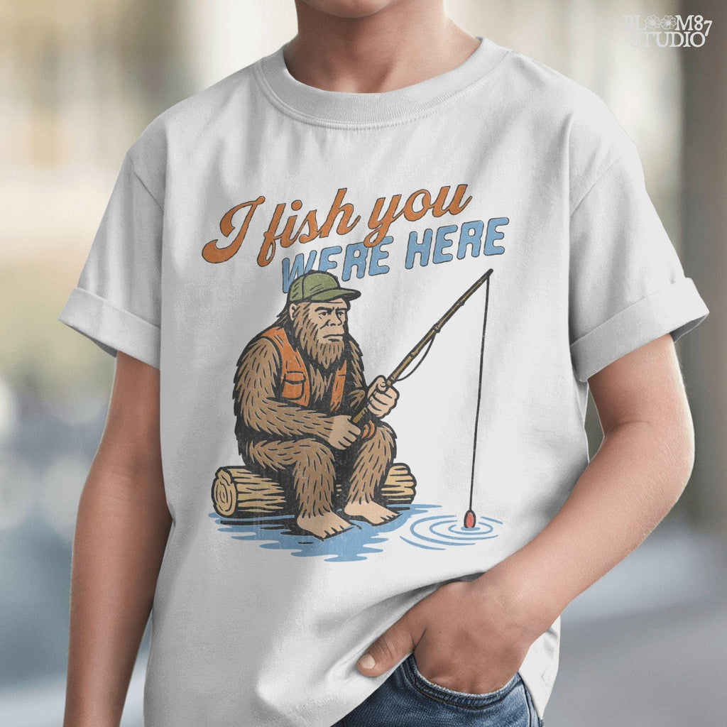 Funny Bigfoot character sitting on log fishing with bobber, wearing orange vest and green cap, with text “I Fish You Were Here”