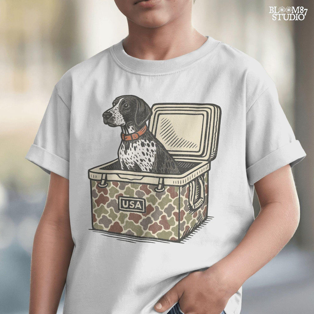 German Shorthaired Pointer dog sitting inside camouflage cooler labeled “USA,” in rustic cartoon patriotic style