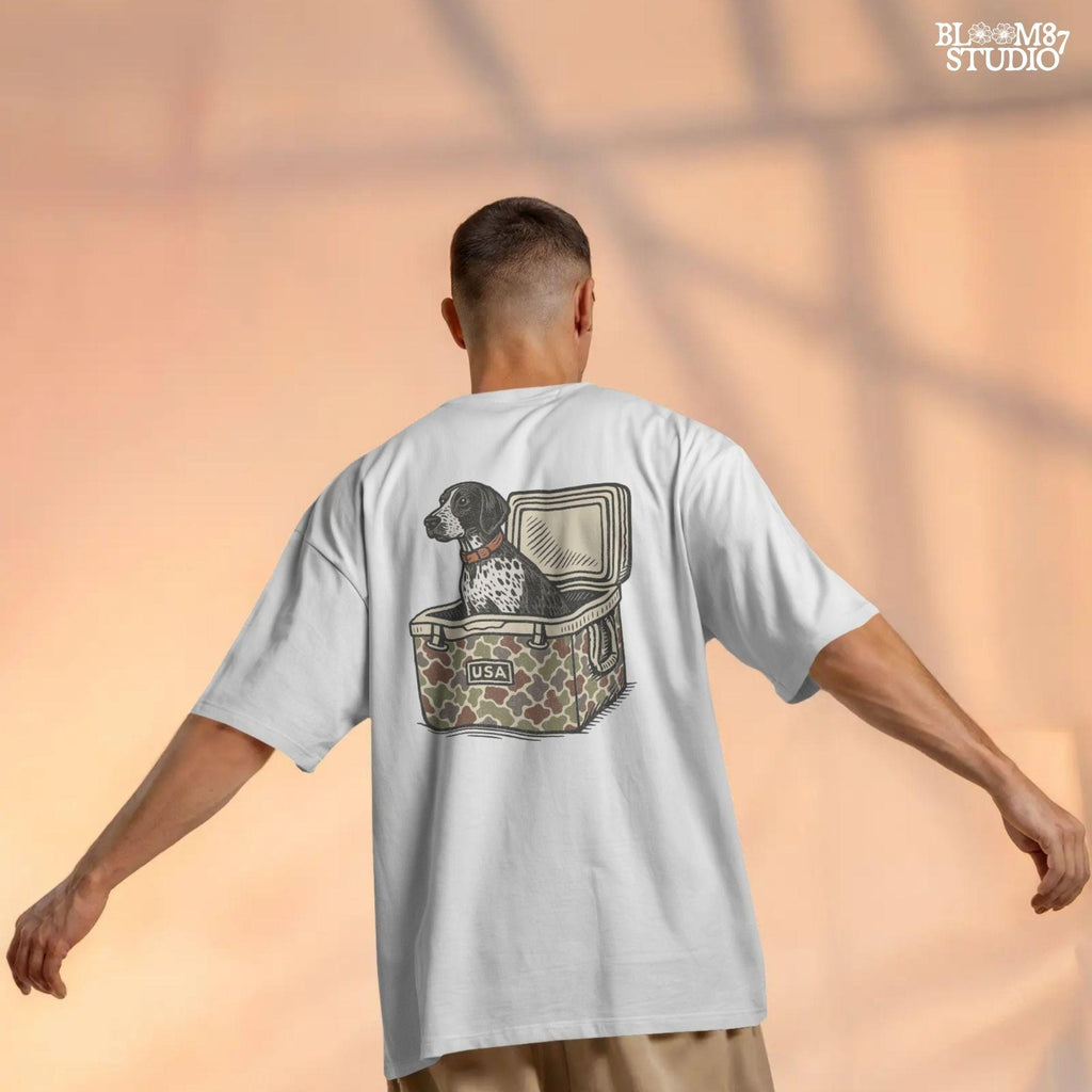 German Shorthaired Pointer dog sitting inside camouflage cooler labeled “USA,” in rustic cartoon patriotic style