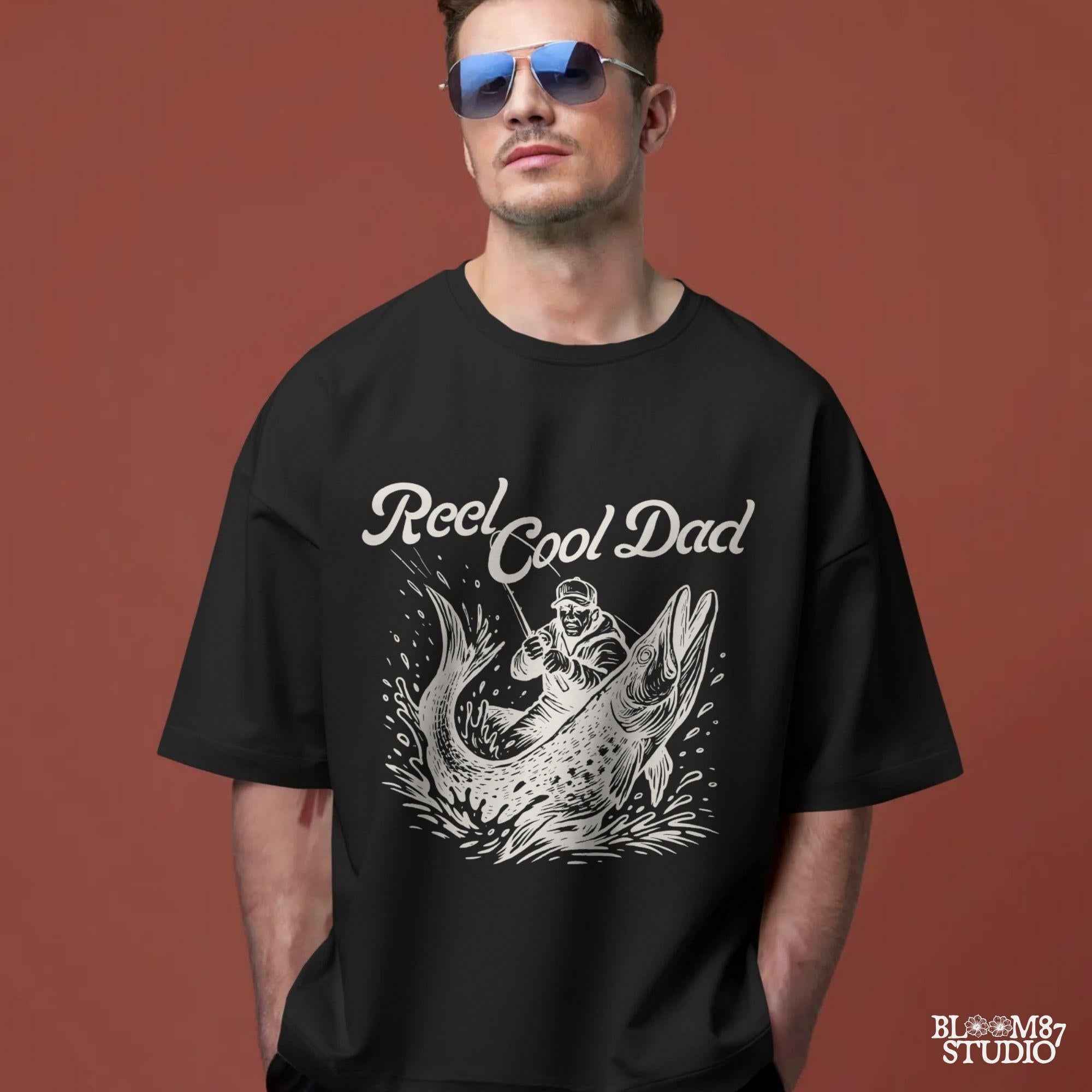 Illustration of a father reeling in a giant fish with bold text “Reel Cool Dad,” perfect for Father’s Day or fishing-themed gifts.