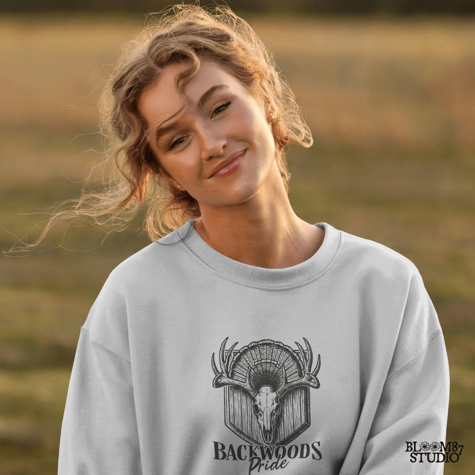 Rustic design of a deer skull with antlers and a turkey fan backdrop above the words “Backwoods Pride,” perfect for country and hunting themes.