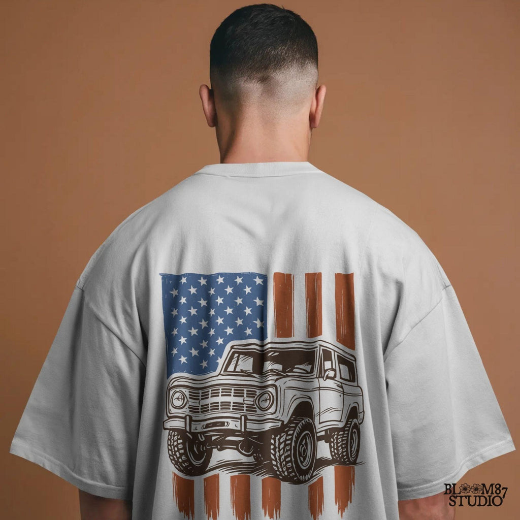 Vintage 4x4 Bronco-style off-road truck with bold tires over a distressed American flag, perfect for patriotic truck lovers and USA-themed designs.
