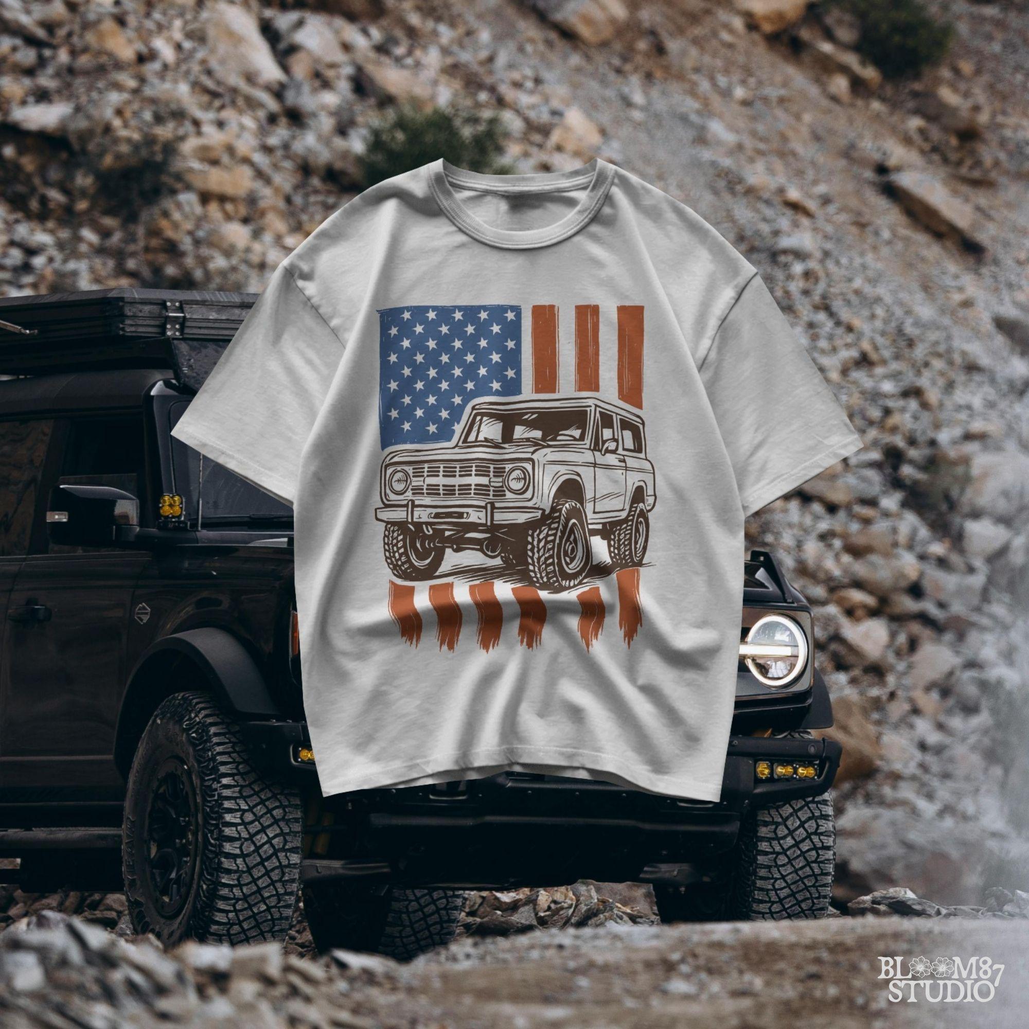 Vintage 4x4 Bronco-style off-road truck with bold tires over a distressed American flag, perfect for patriotic truck lovers and USA-themed designs.