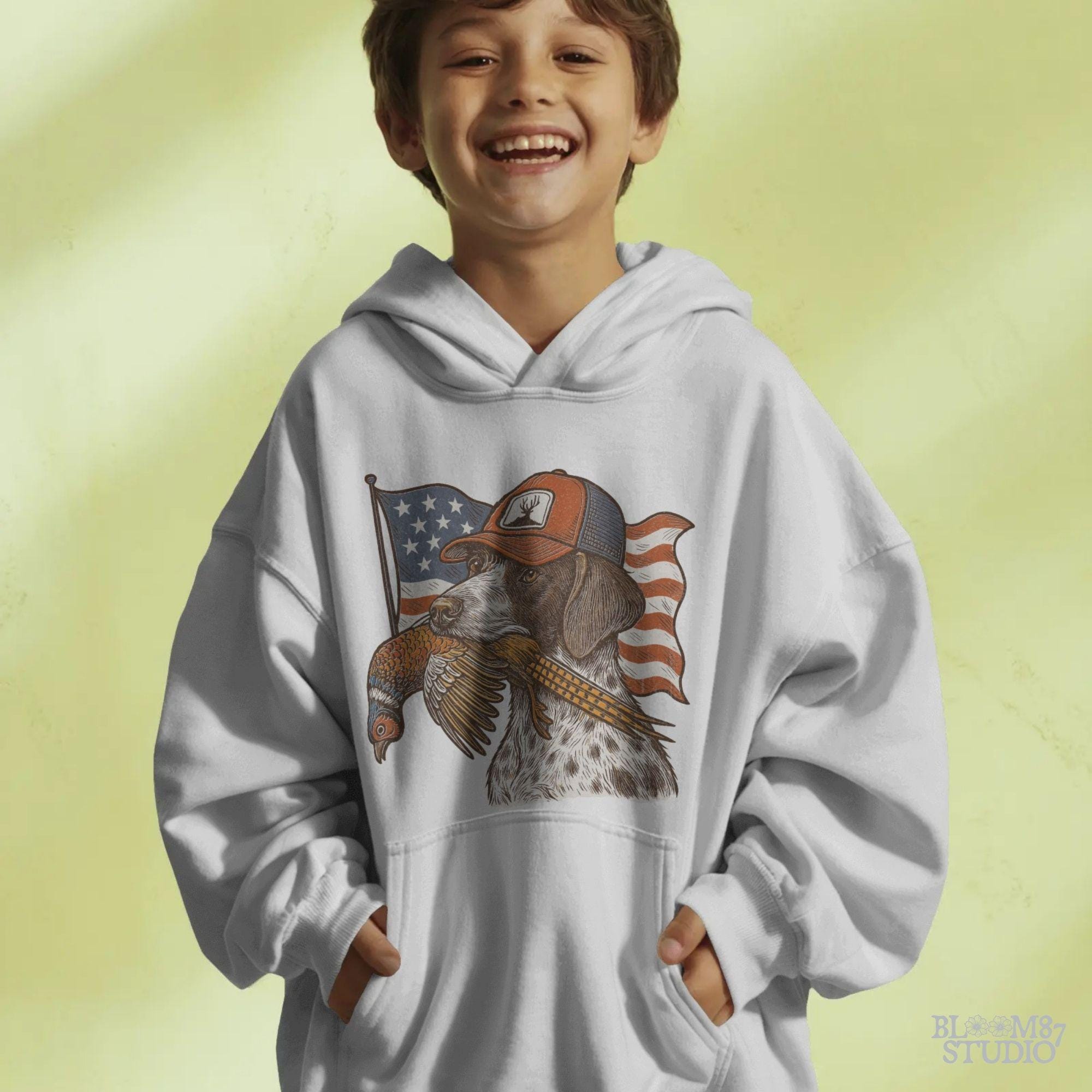 Hunting dog wearing a cap and holding a pheasant in its mouth, with a waving American flag in the background.