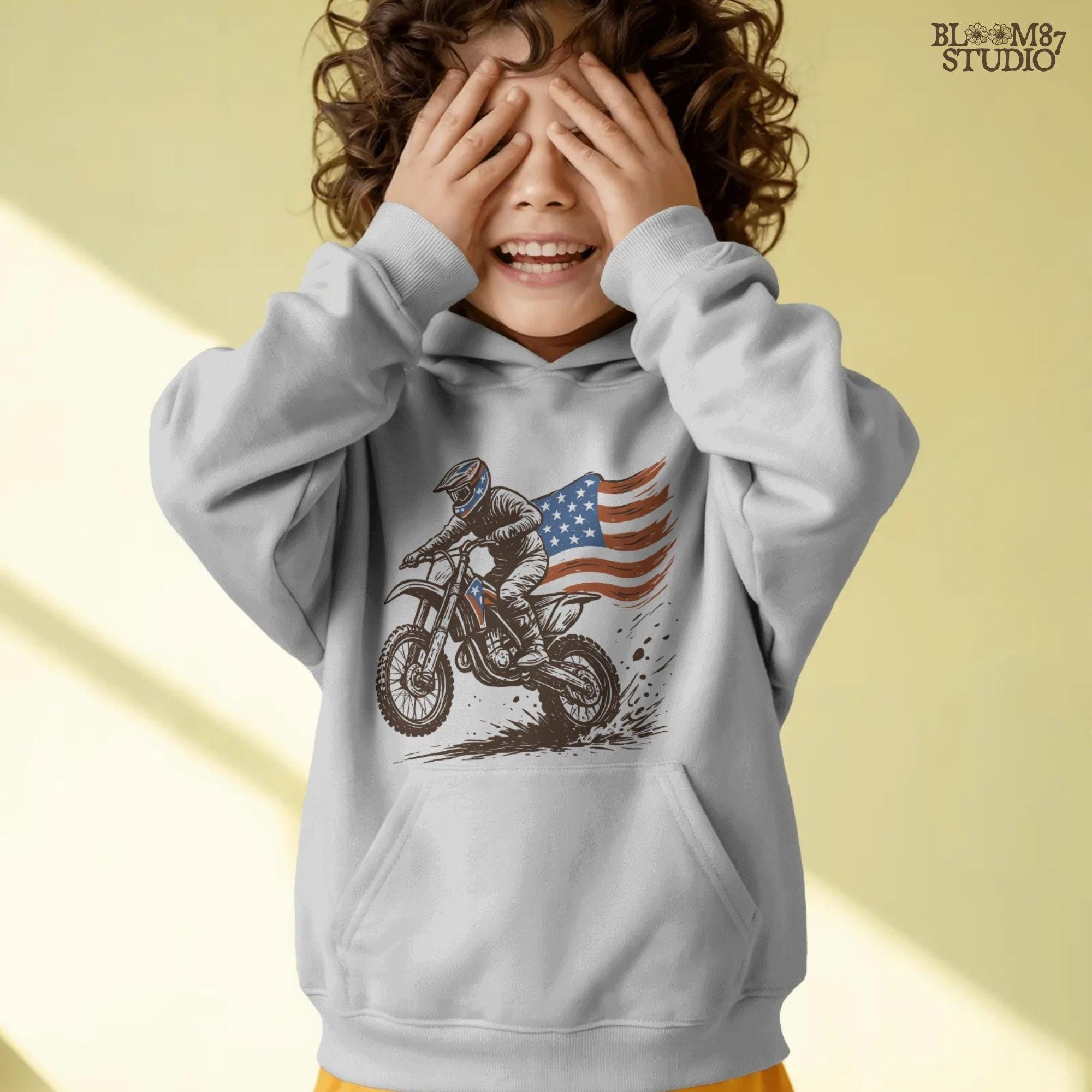 Patriotic motocross rider doing a dirt jump on a dirt bike with the American flag flowing behind, in a bold western vintage style illustration.