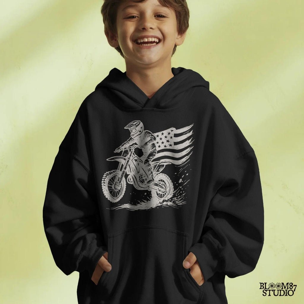 Patriotic motocross rider doing a dirt jump on a dirt bike with the American flag flowing behind, in a bold western vintage style illustration.