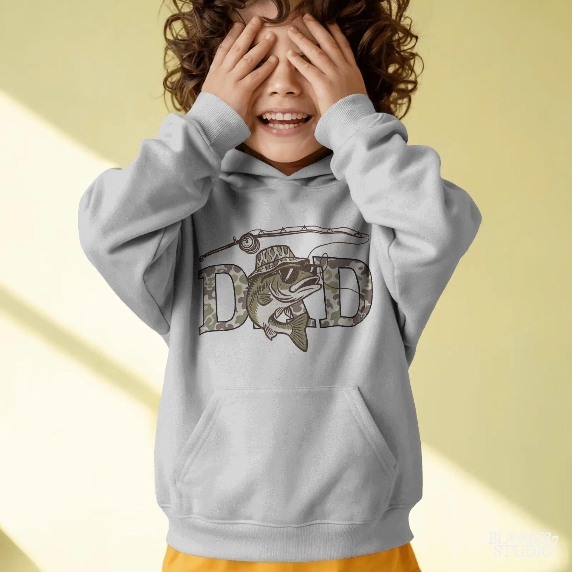 A funny camo bass fish wearing sunglasses and a camo bucket hat, with large camouflage DAD lettering and a fishing pole above.