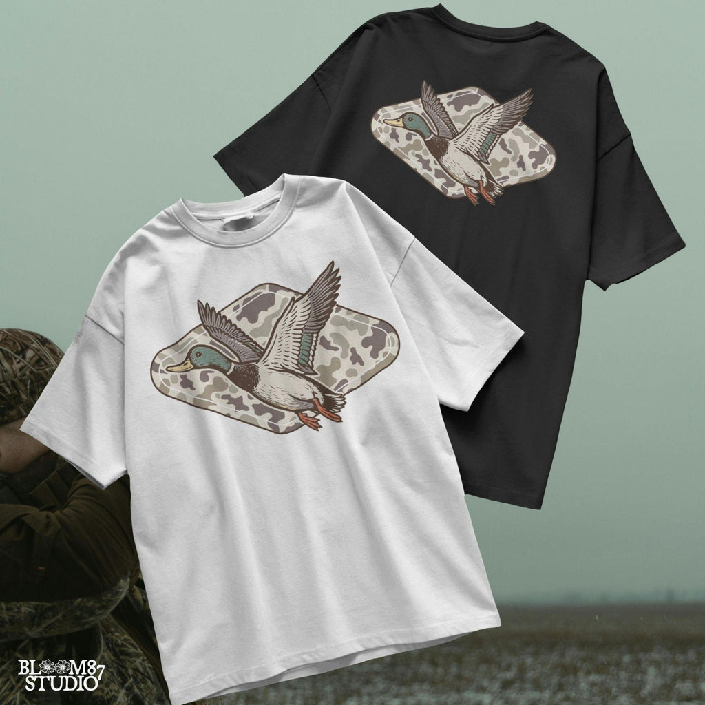 Flying mallard duck over old-school marsh camouflage background, designed in vintage hunting style for southern outdoorsman-themed crafts.