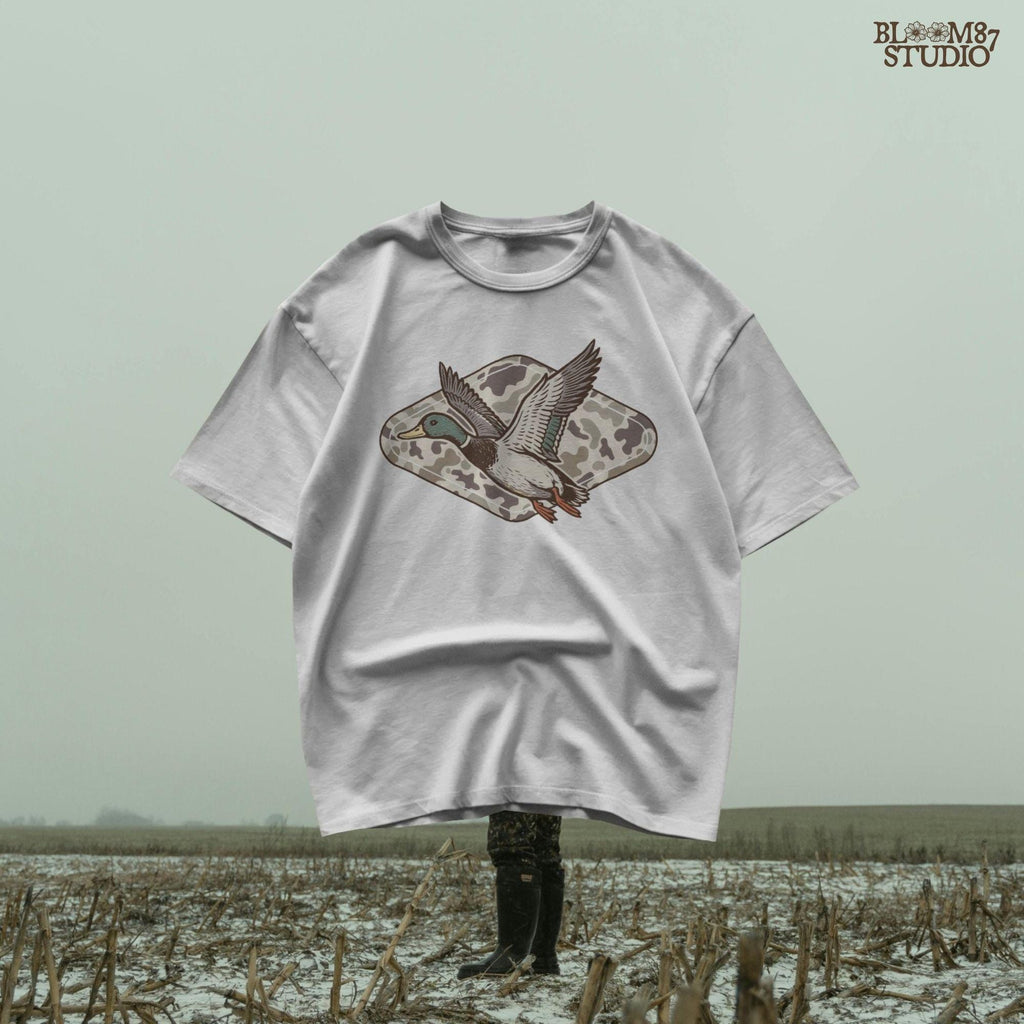 Flying mallard duck over old-school marsh camouflage background, designed in vintage hunting style for southern outdoorsman-themed crafts.