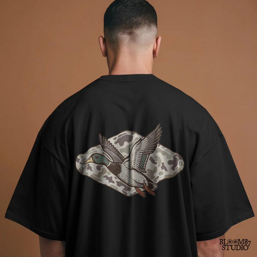 Flying mallard duck over old-school marsh camouflage background, designed in vintage hunting style for southern outdoorsman-themed crafts.