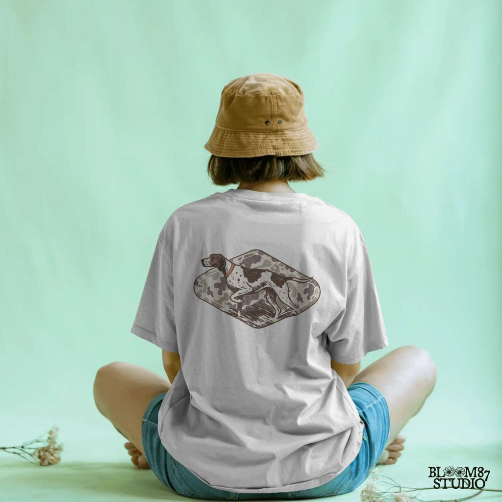 Illustration of a pointer hunting dog in a classic pointing stance on a vintage camo background, designed for upland hunting and outdoor-themed projects.