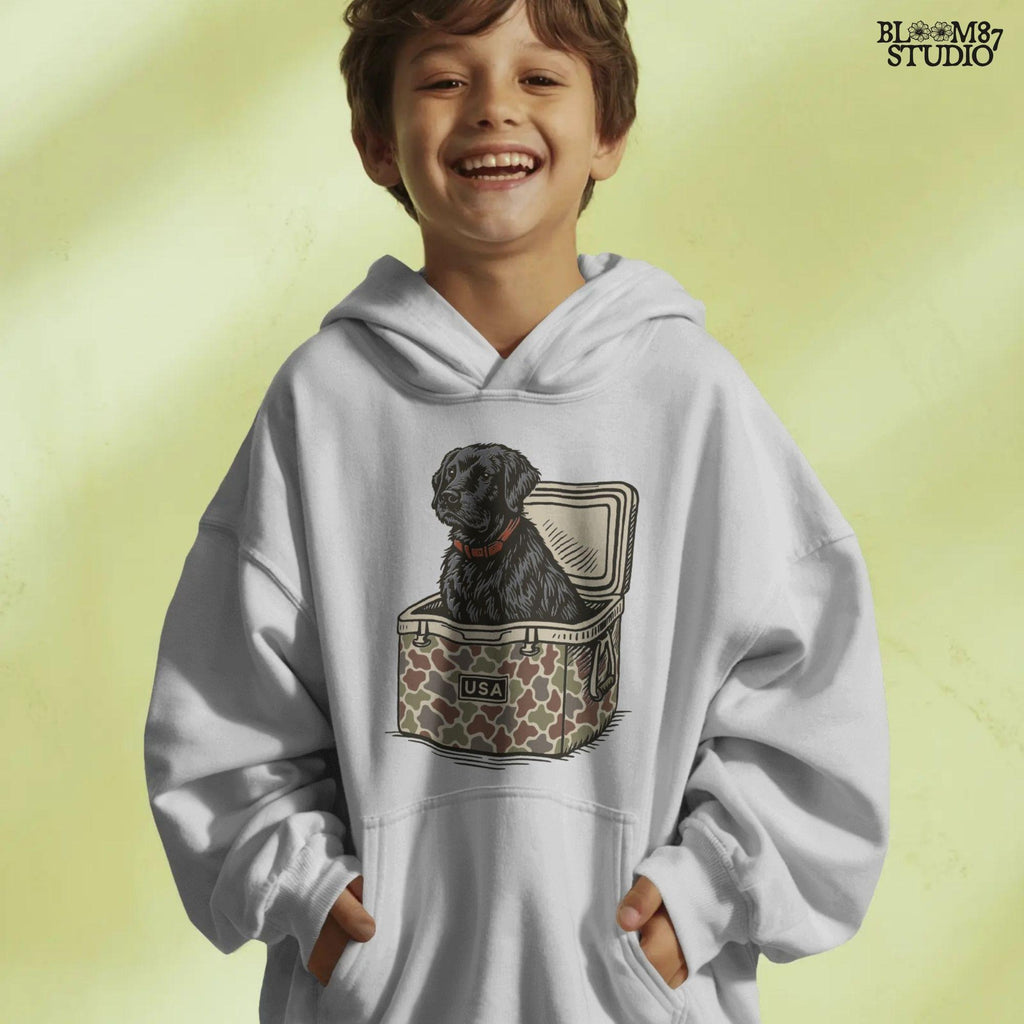 Hand-drawn black Labrador retriever sitting in a camouflage cooler labeled “USA,” designed for sublimation and hunting-themed merchandise.