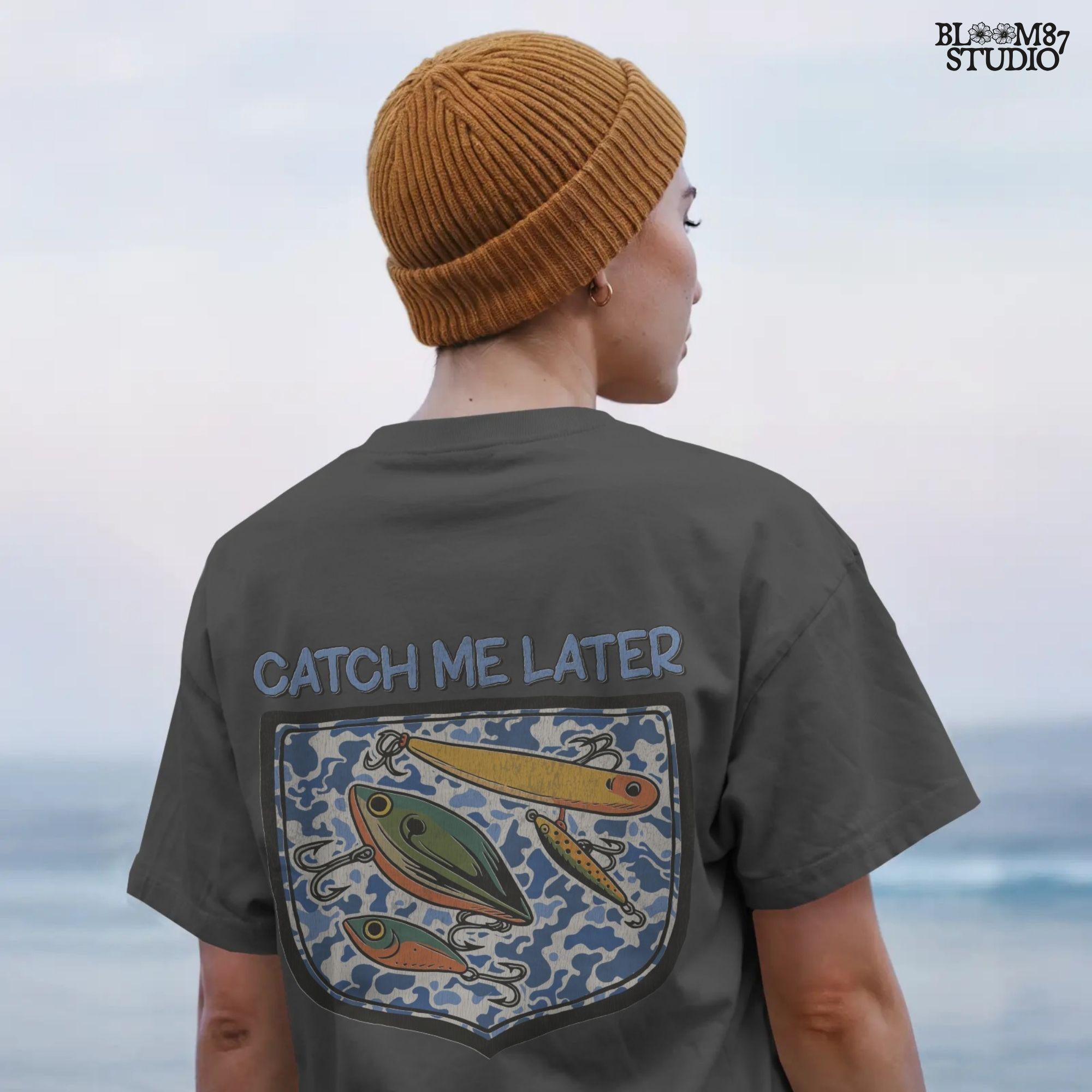Funny “Catch Me Later” text above a faux blue camo pocket with colorful fishing lures, designed for sublimation printing on fisherman-themed apparel.