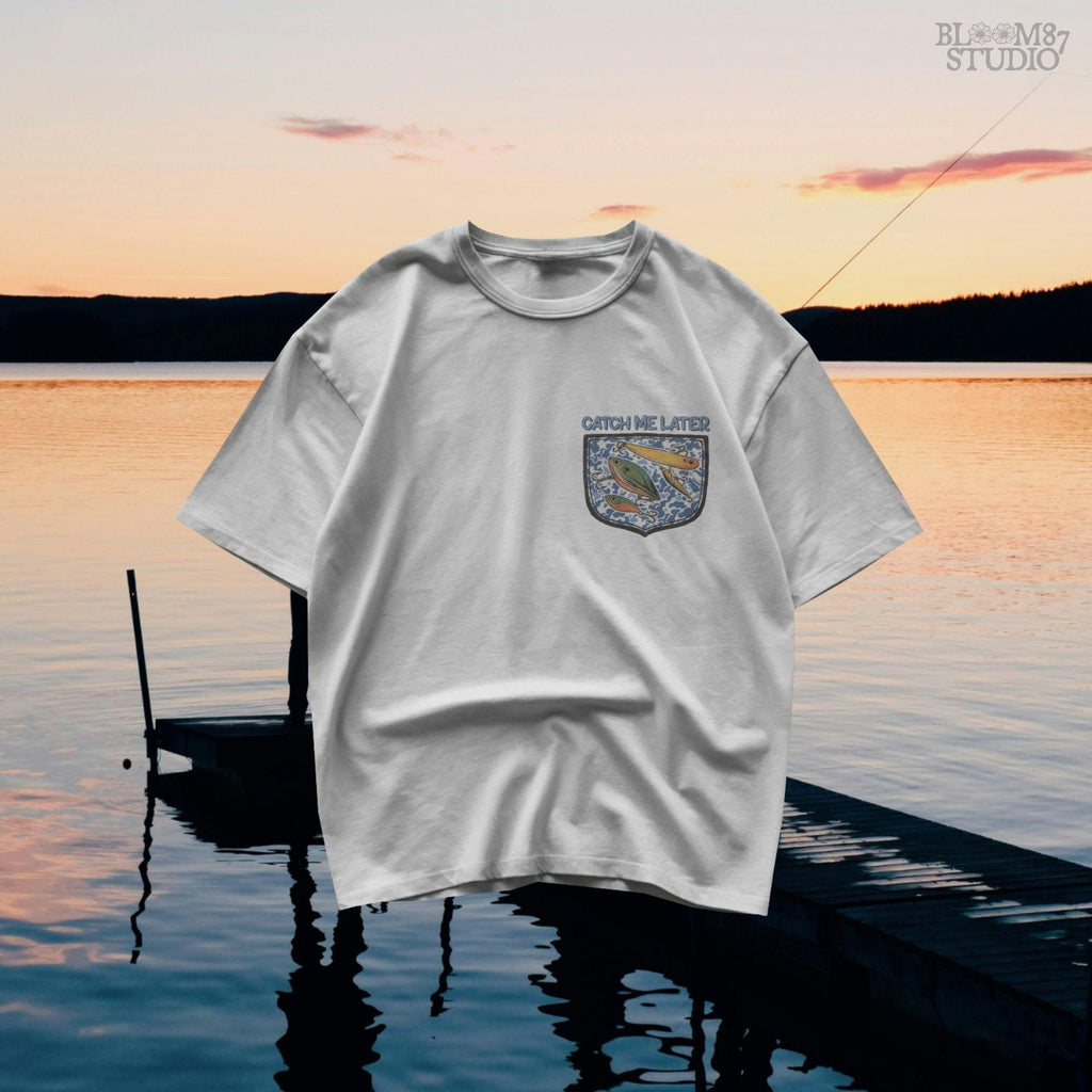 Funny “Catch Me Later” text above a faux blue camo pocket with colorful fishing lures, designed for sublimation printing on fisherman-themed apparel.