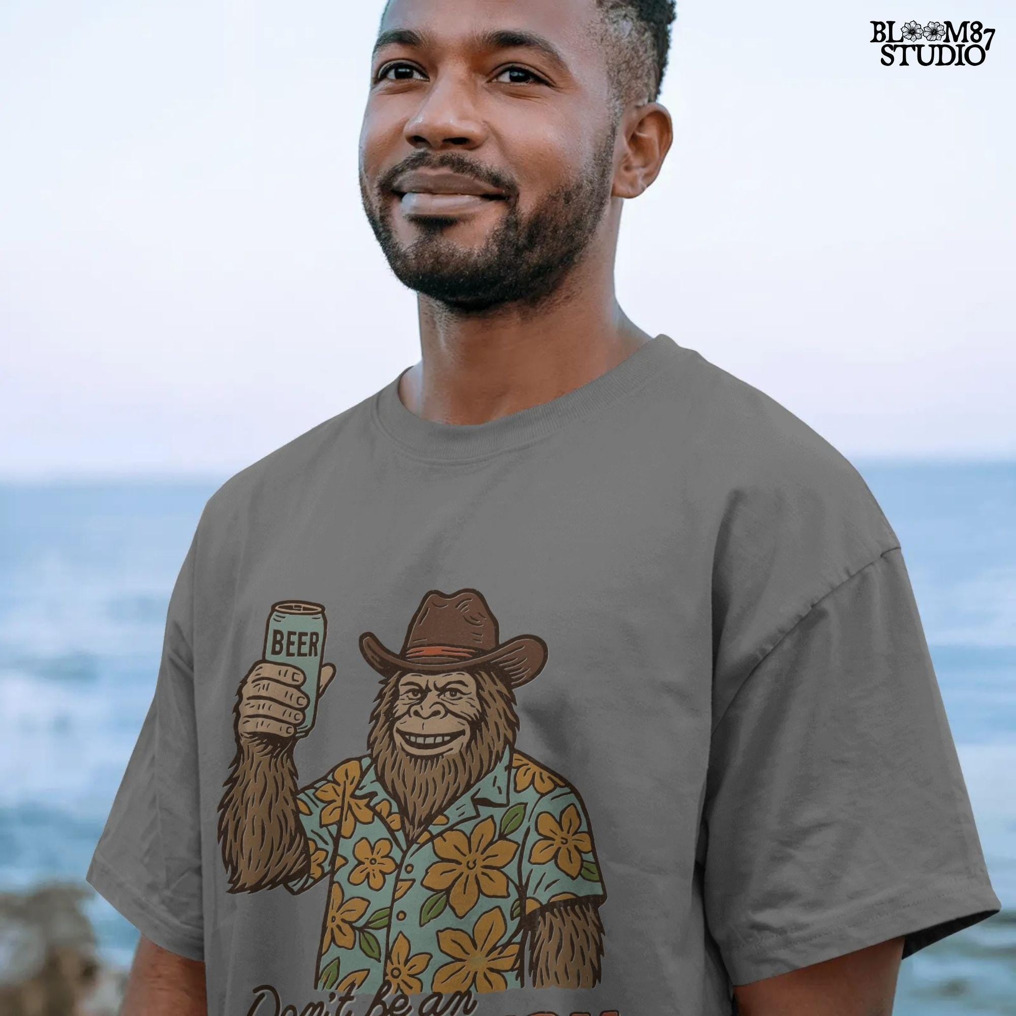 Retro cartoon Sasquatch in floral shirt holding a beer can with text “Don’t Be an Assquatch,” perfect for funny camping or summer designs