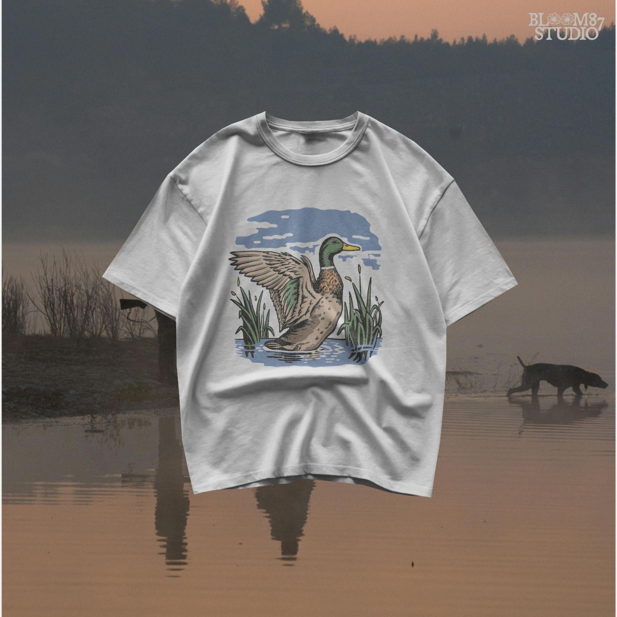 Vintage illustration of a mallard duck with wings spread standing in a pond with reeds and a cloudy blue sky – rustic nature sublimation PNG.