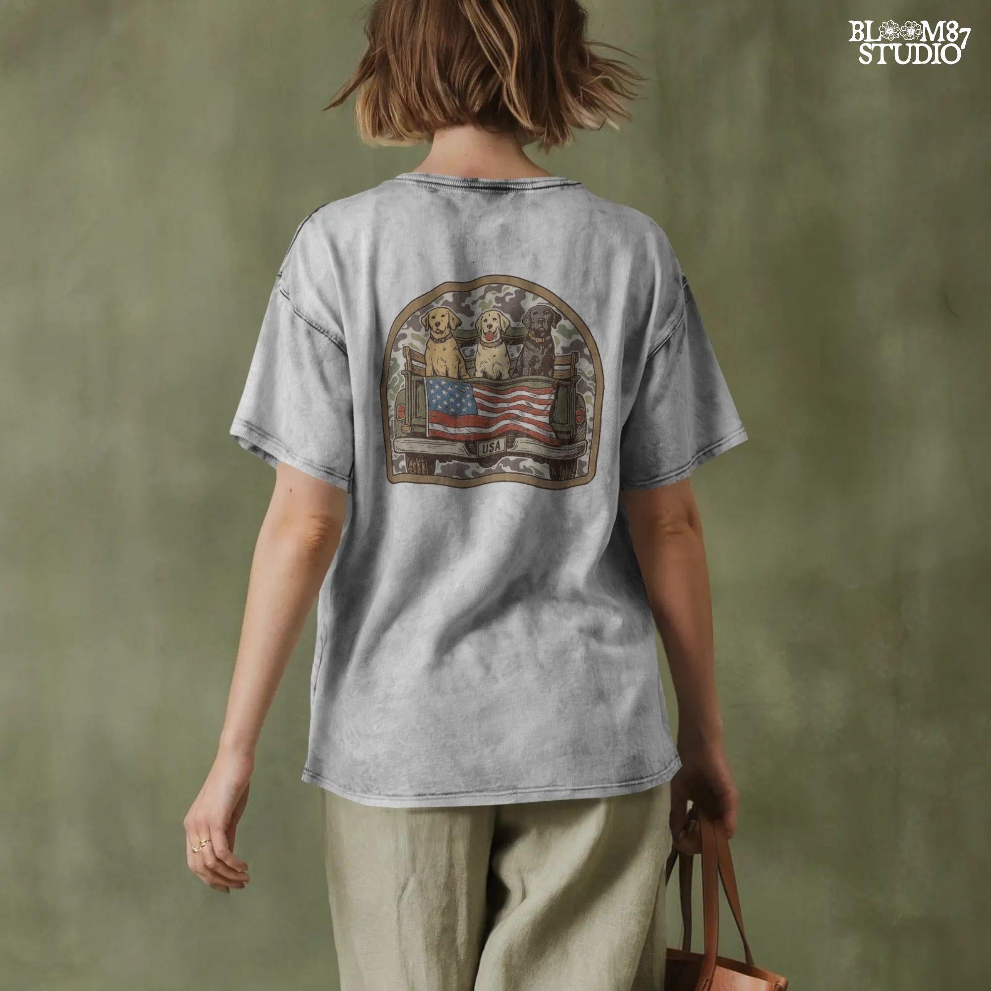 Three Labrador retrievers — yellow, chocolate, and black — sitting on the back of a green camouflage pickup truck with an American flag and the words “Local Boy” underneath.