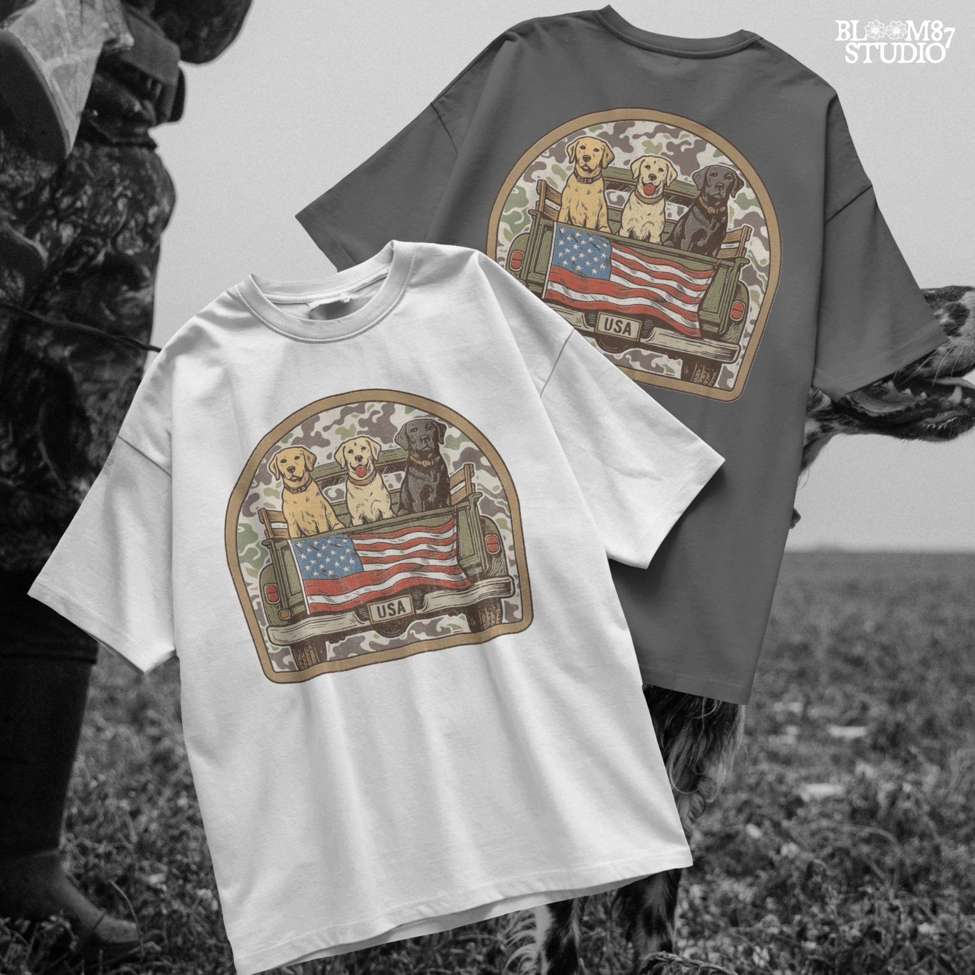 Three Labrador retrievers — yellow, chocolate, and black — sitting on the back of a green camouflage pickup truck with an American flag and the words “Local Boy” underneath.