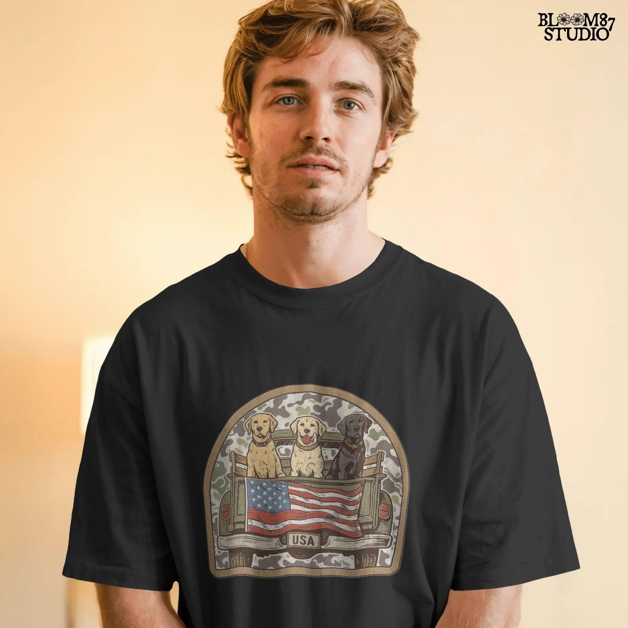 Three Labrador retrievers — yellow, chocolate, and black — sitting on the back of a green camouflage pickup truck with an American flag and the words “Local Boy” underneath.