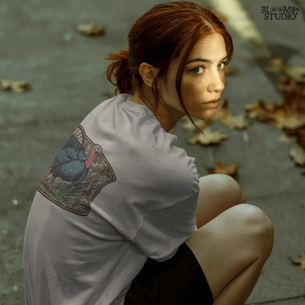 Illustration of a strutting wild turkey in front of a detailed fall camouflage background with brown and orange leaves, designed for sublimation on hunting shirts and Thanksgiving outdoor gear.