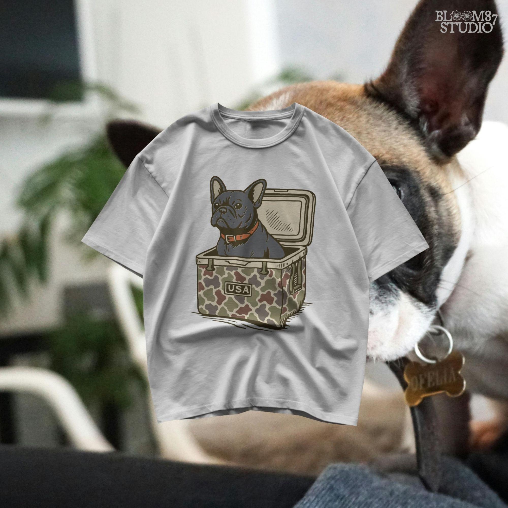 French Bulldog sitting inside a camouflage USA cooler, wearing a red collar, in rustic outdoor style — perfect for patriotic dog lovers and sublimation use.