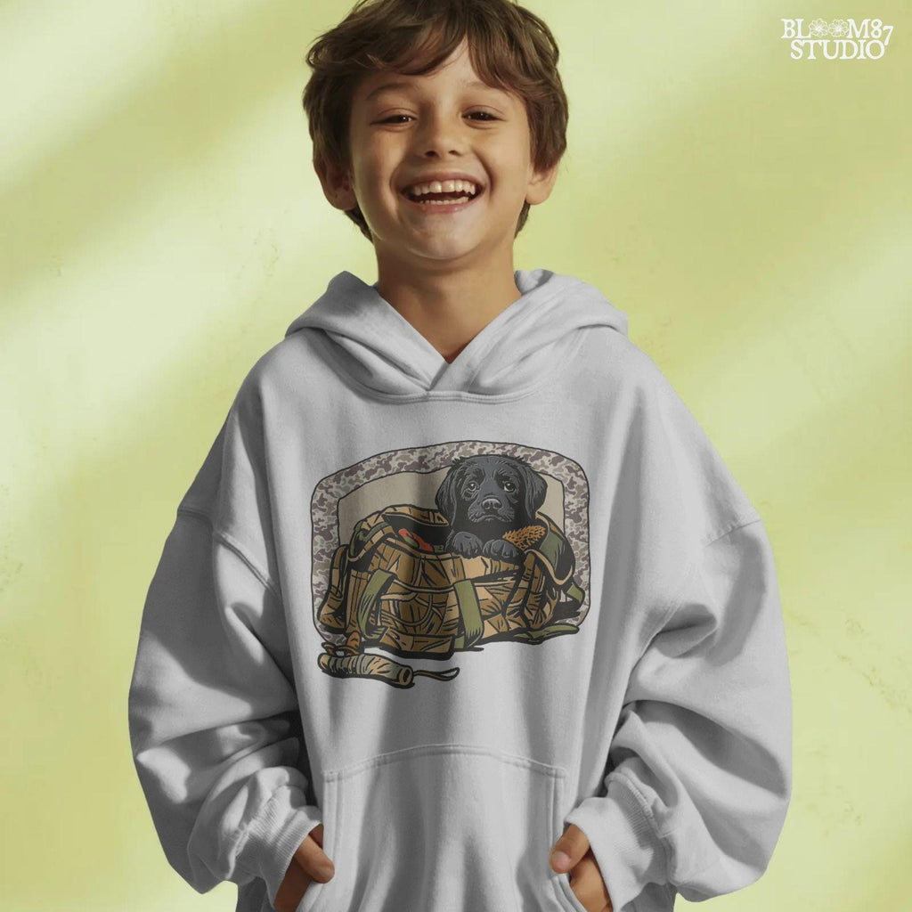 Black Labrador puppy in a camo hunting bag, framed in camouflage pattern, ideal for waterfowl and duck hunting sublimation art.