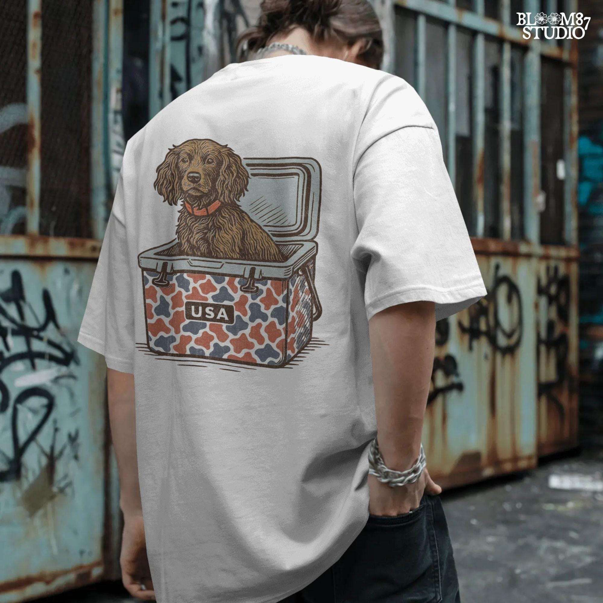 Sporting dog (spaniel type) sitting in a patriotic red-white-blue camo cooler labeled “USA” – sublimation PNG for southern dog lovers and summer crafts.