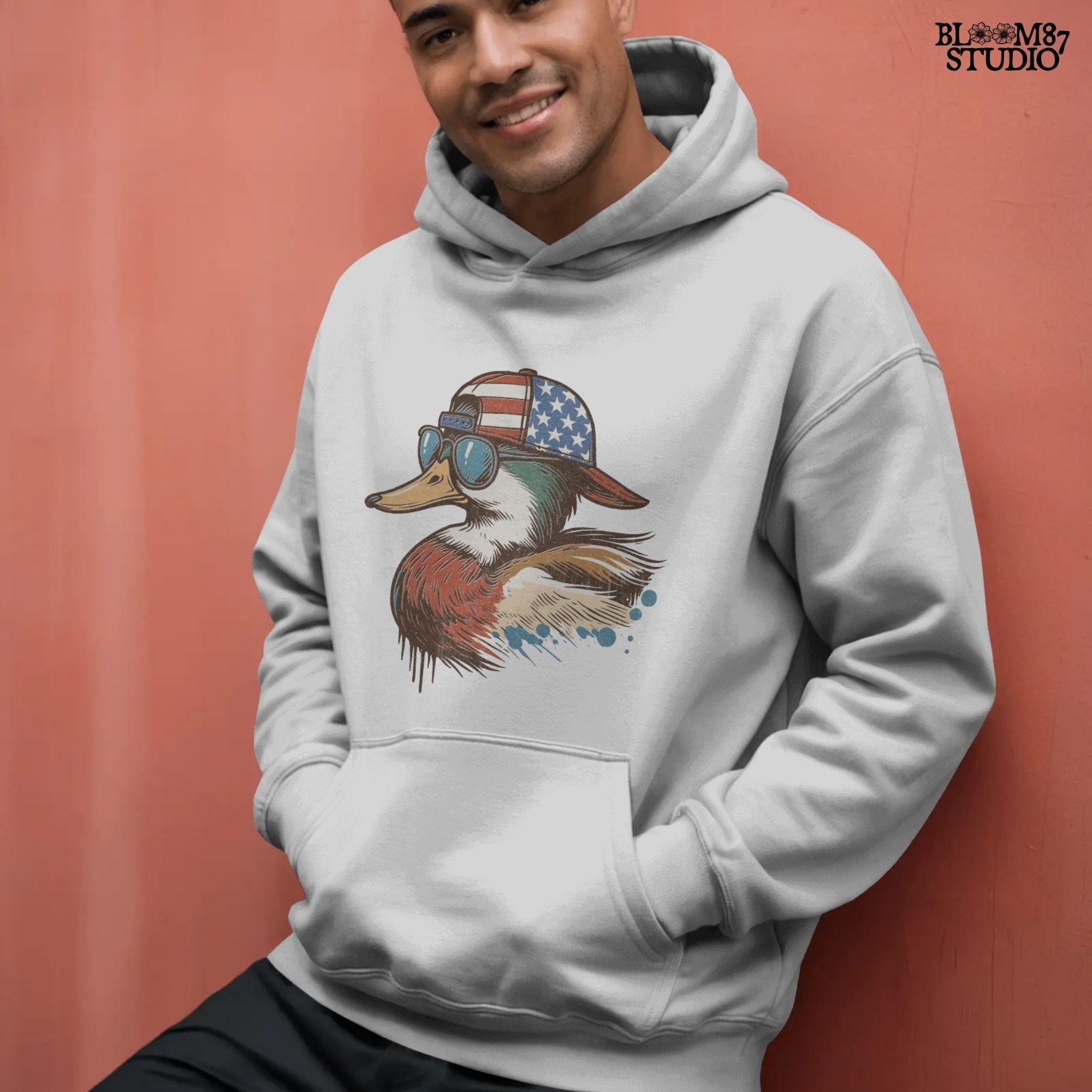 Cartoon mallard duck wearing American flag hat and sunglasses in a humorous patriotic style, with bold colors and splash detail