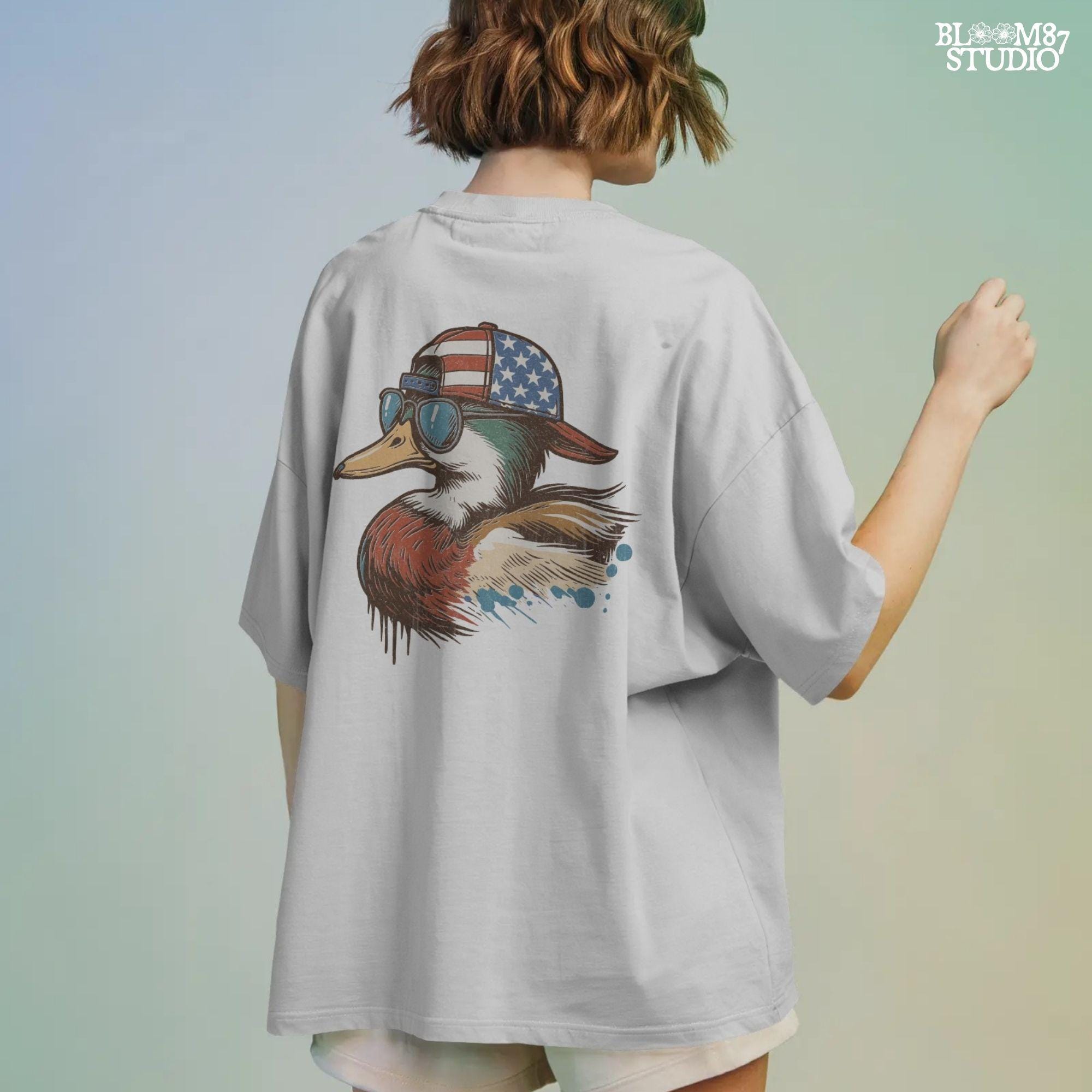 Cartoon mallard duck wearing American flag hat and sunglasses in a humorous patriotic style, with bold colors and splash detail