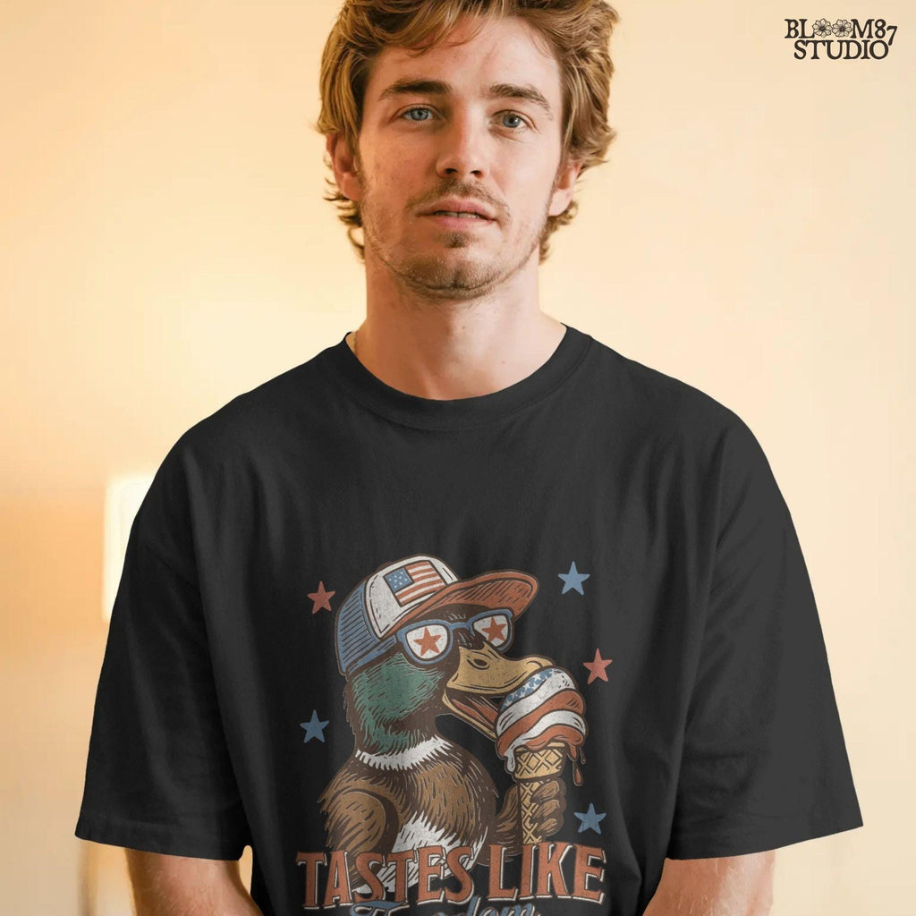 Funny cartoon duck wearing USA hat and star sunglasses, licking patriotic ice cream cone with “Tastes Like Freedom” text and red-white-blue stars