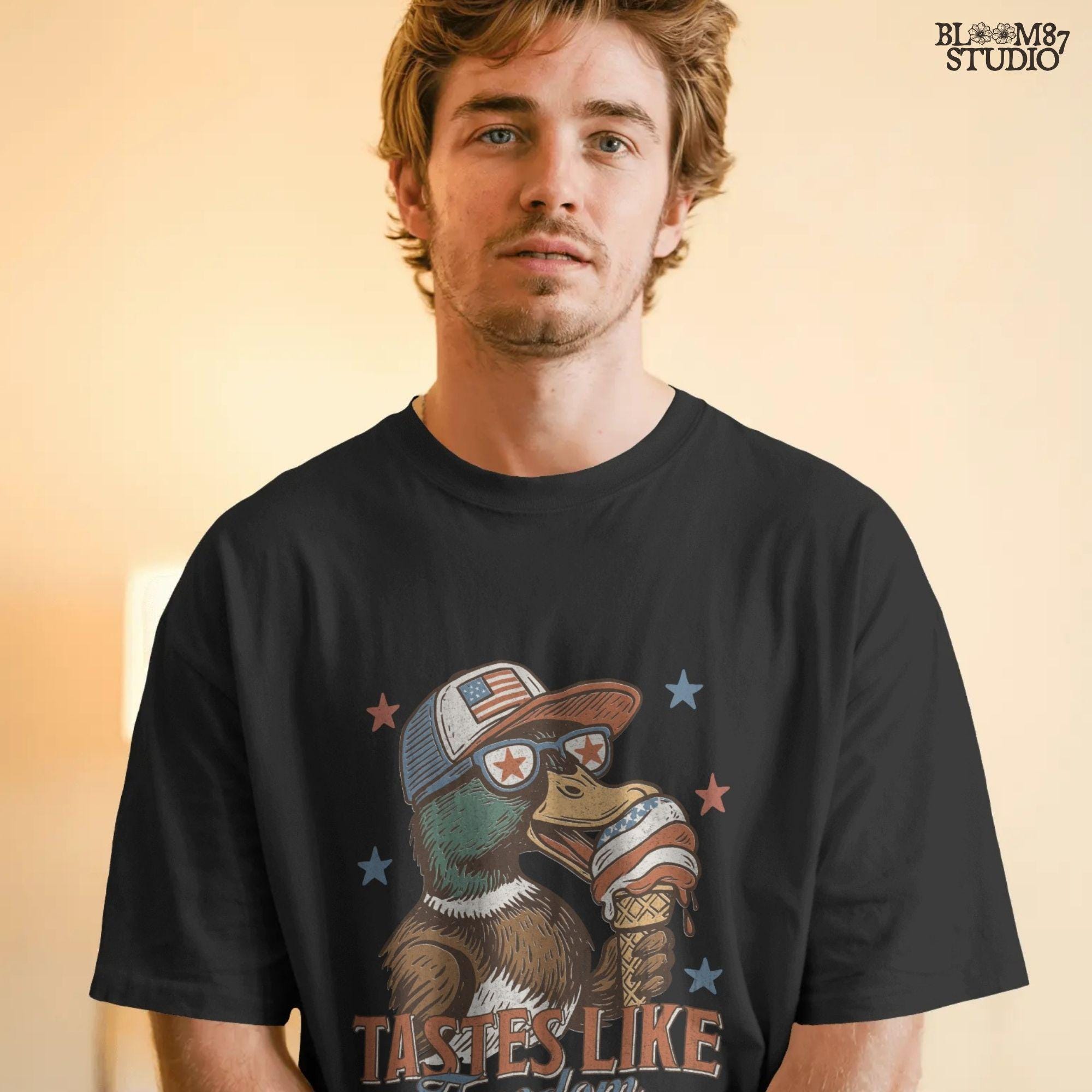 Funny cartoon duck wearing USA hat and star sunglasses, licking patriotic ice cream cone with “Tastes Like Freedom” text and red-white-blue stars