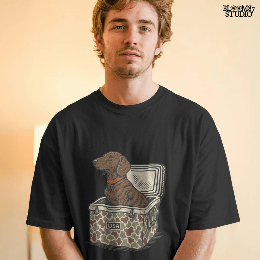 Brown dachshund dog sitting in camouflage cooler labeled “USA” with a red collar, drawn in patriotic cartoon style