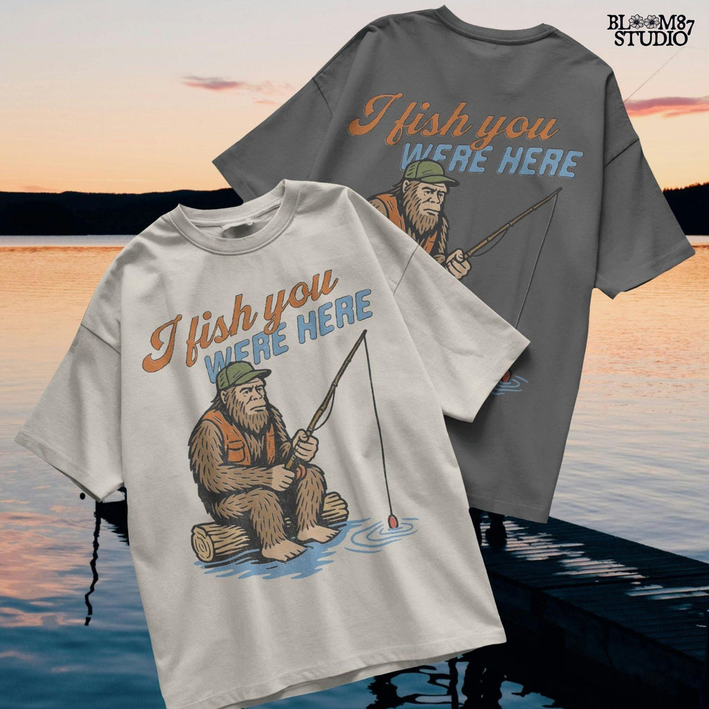 Funny Bigfoot character sitting on log fishing with bobber, wearing orange vest and green cap, with text “I Fish You Were Here”